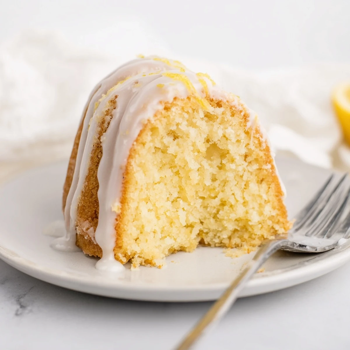A lovely slice of Lemon Drizzle Bundt Cake, with a glistening lemon glaze on top.