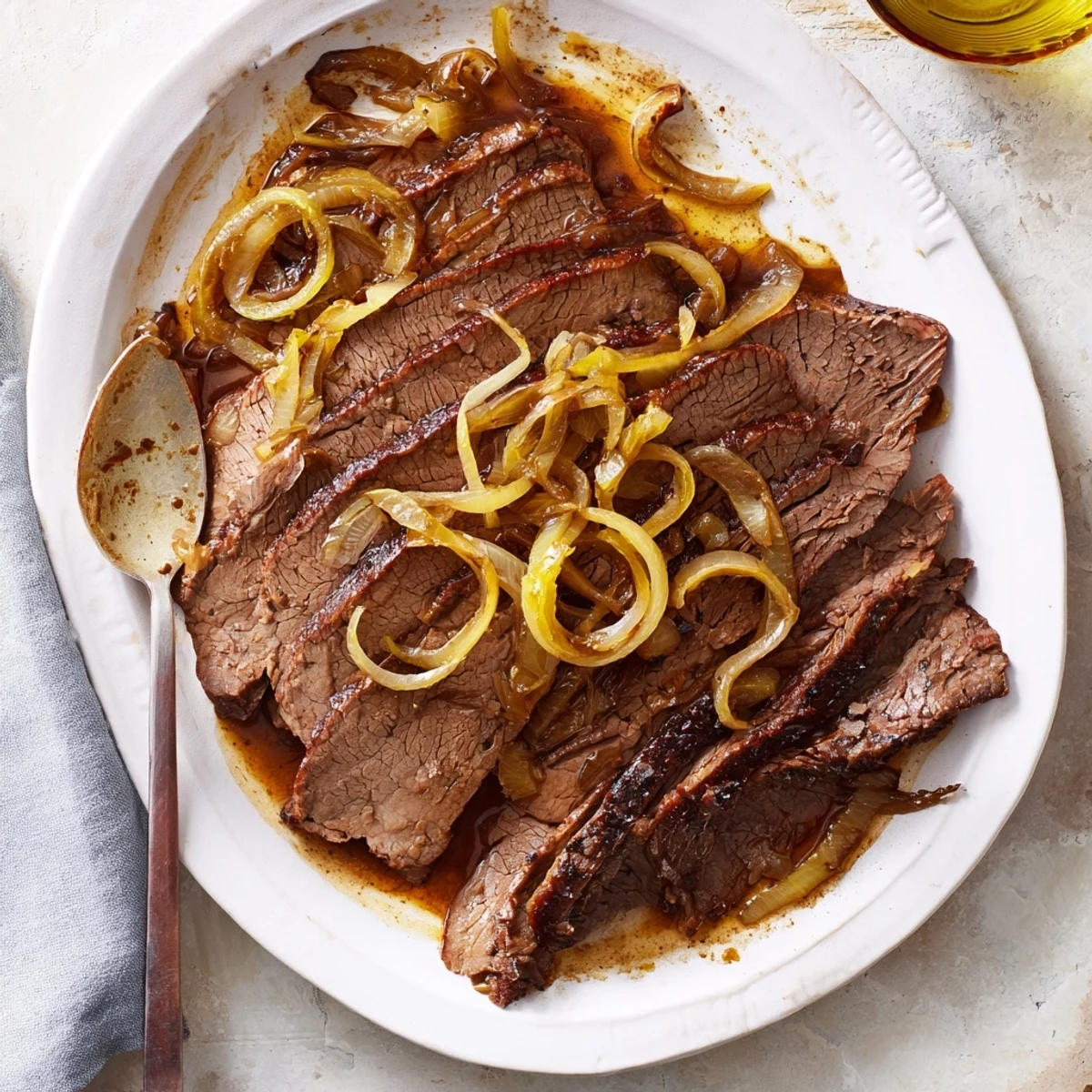 Fork-tender slow cooked beef brisket is pictured, served with rich caramelized onions for a delicious dinner.