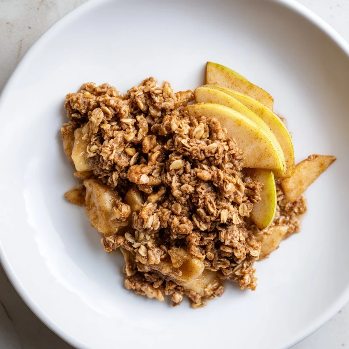 Freshly baked warm apple crisp with a crispy oat topping, promising a comforting, sweet, and fruity treat.