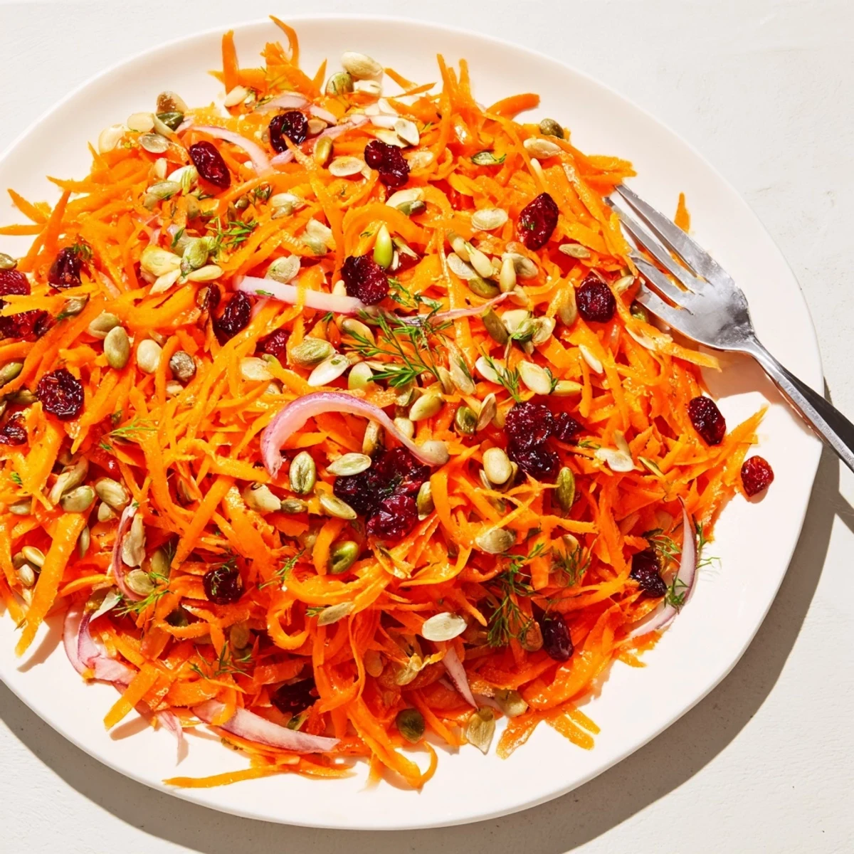 Close-up of a vibrant Raw Carrot Salad, tossed with herbs and vinaigrette—a colorful and healthy dish.