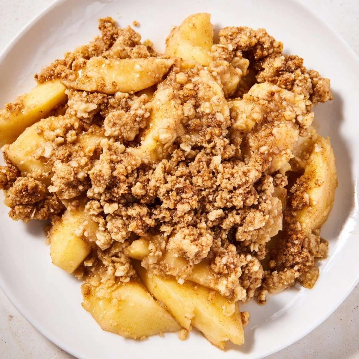 Warm apple crumble, a golden-baked dessert with bubbling apples, ideal for serving with cream.