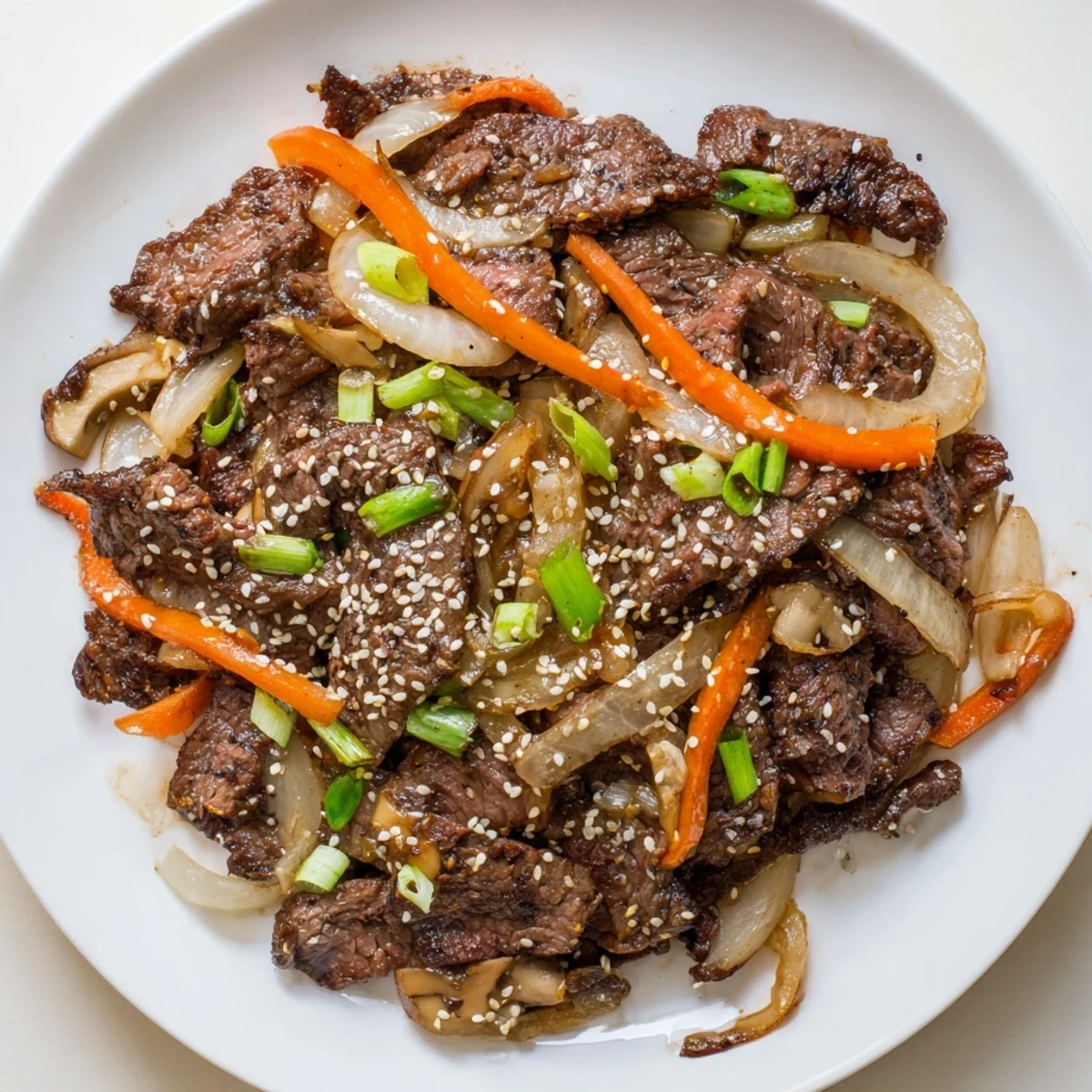 Tender Korean beef stir-fry with glistening vegetables and sesame seeds, perfect over fluffy white rice.