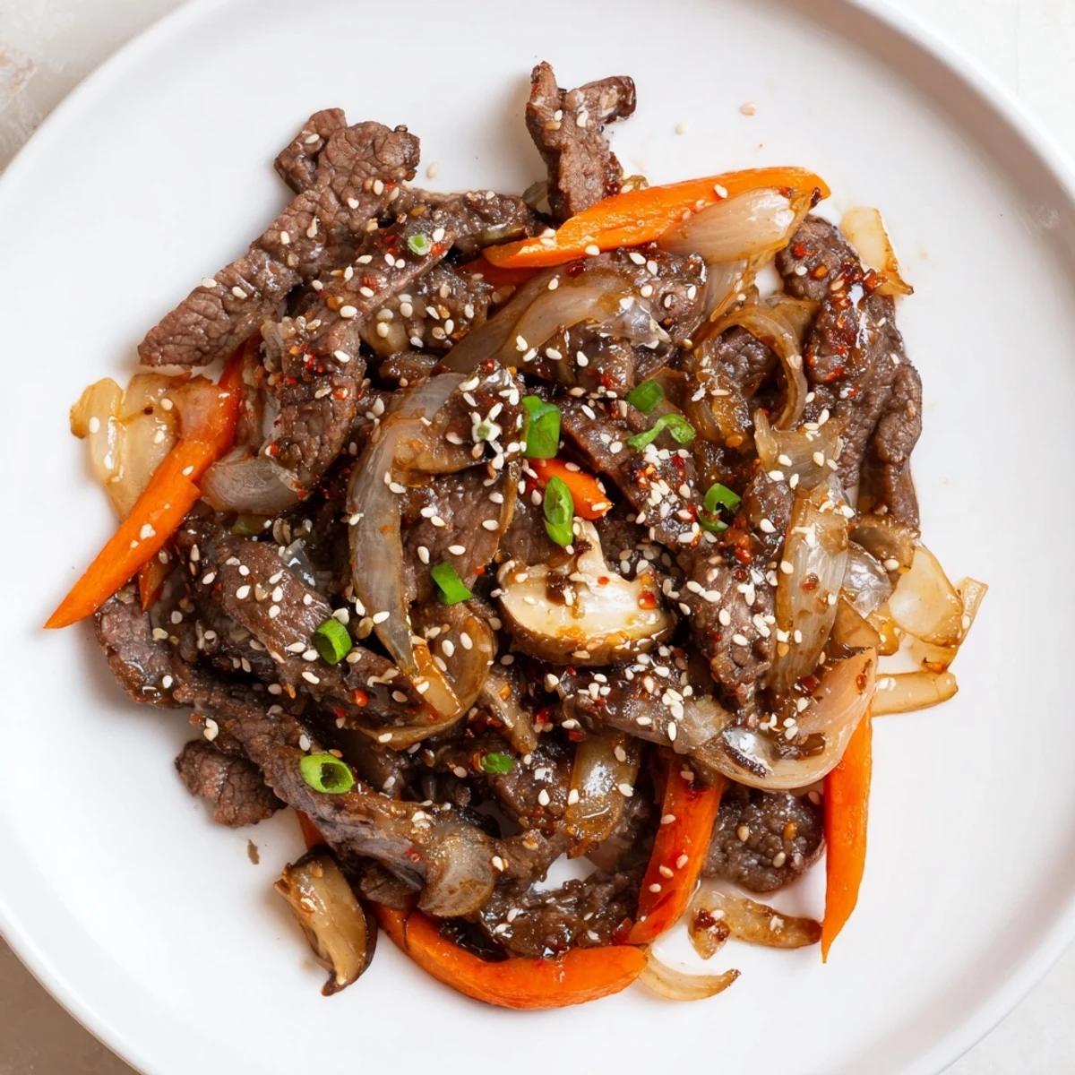 A close-up of savory Korean beef, showing seared beef strips, colorful veggies, and a rich sauce.
