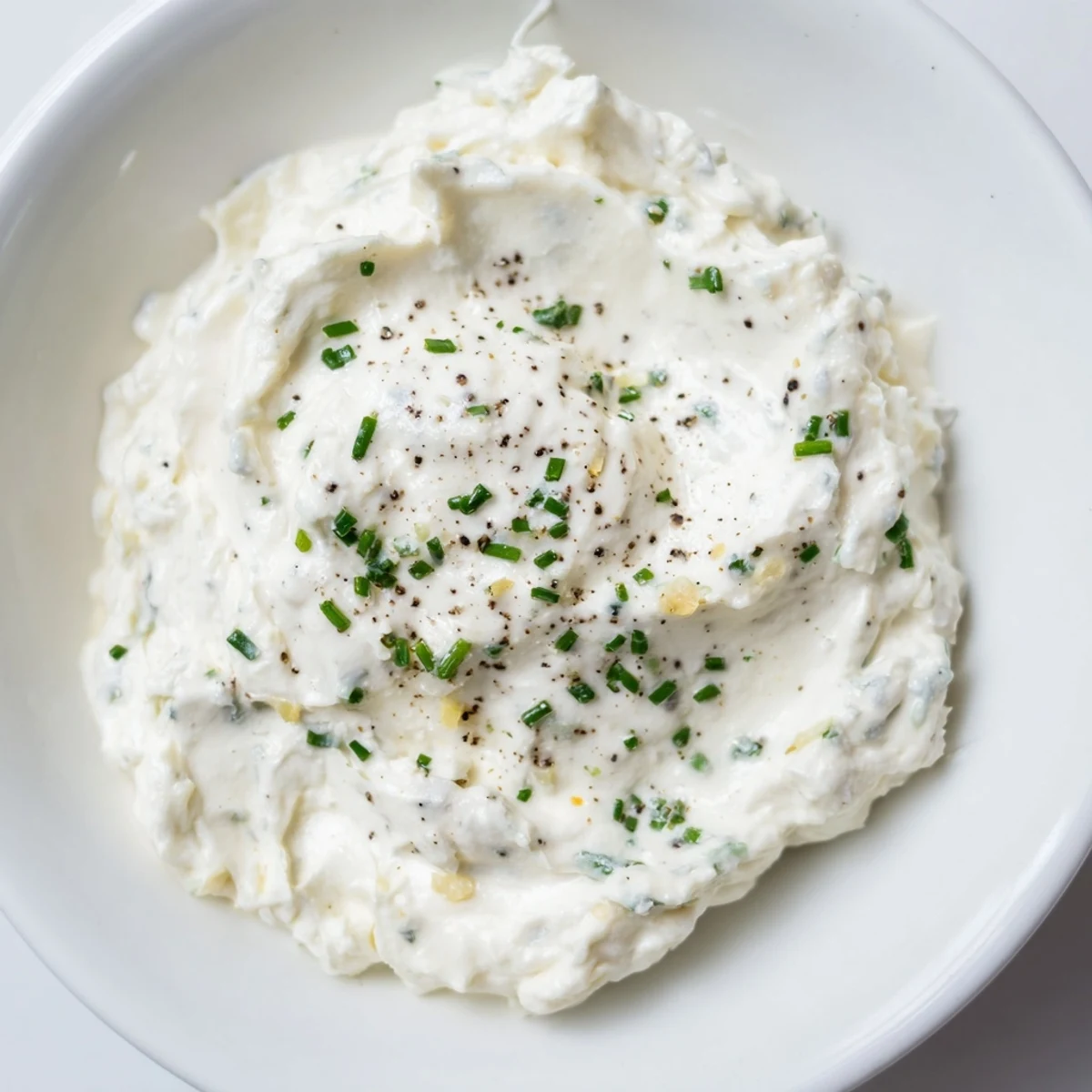 A bowl of creamy garlic dip with fresh herbs, ready for dipping vegetables.