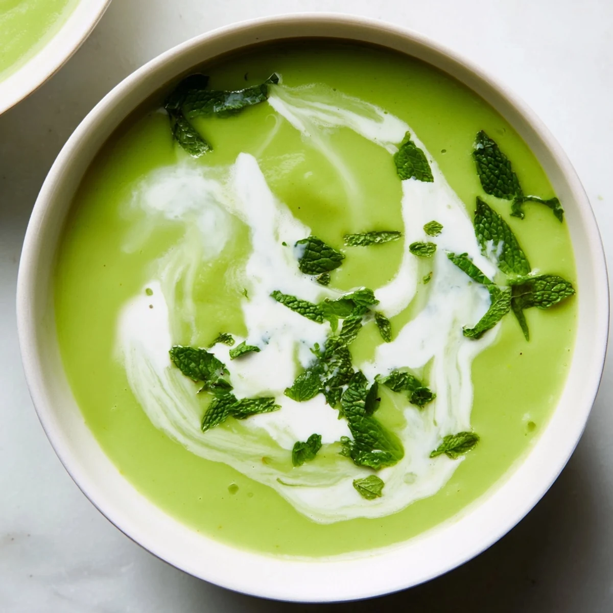 Creamy Pea Soup, a vibrant green, silky smooth soup garnished with fresh mint and cream swirl.