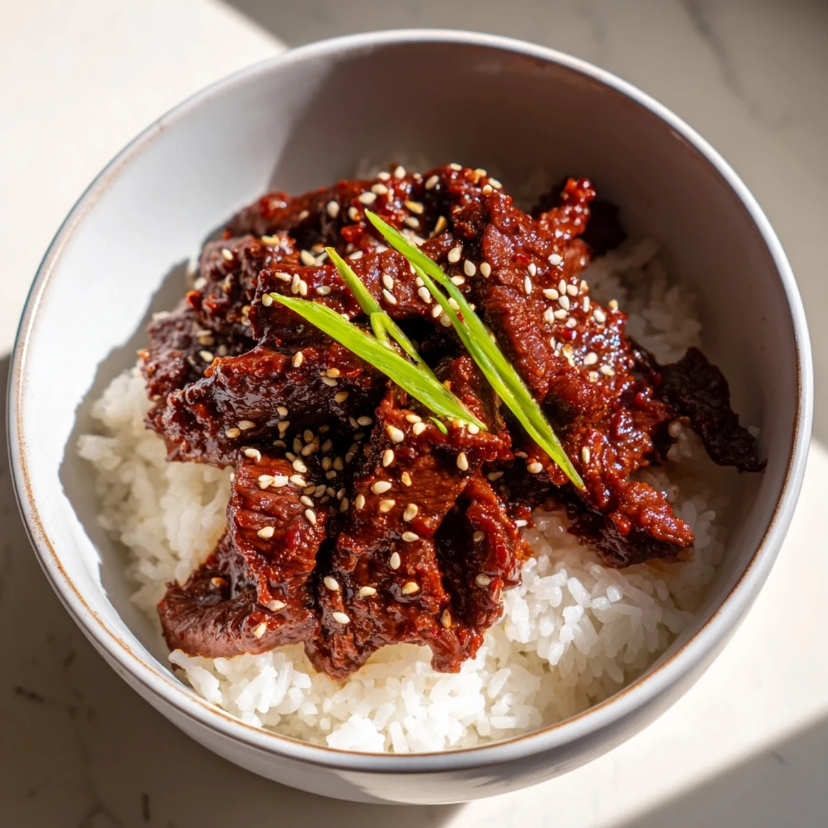 Colorful Spicy Korean Beef Bowl with Rice featuring tender beef glazed in a glossy red sauce.