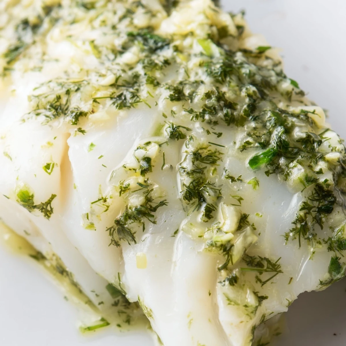 Flaky and tender Baked Cod with Herb Butter baked to perfection, drizzled with fresh lemon juice on a plate.