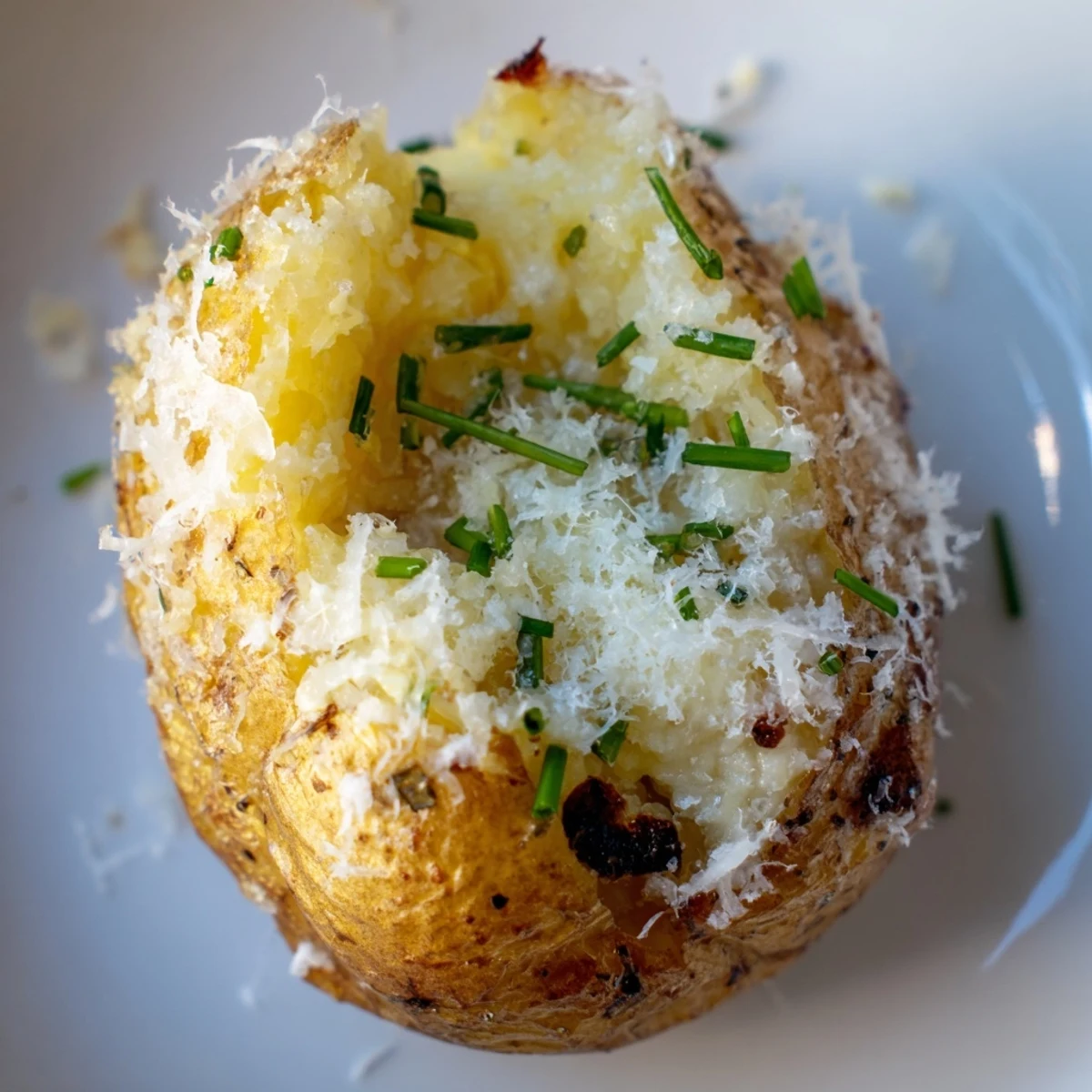 A crispy and fluffy Garlic Parmesan Smashed Potatoes with Chives garnished with chopped herbs.