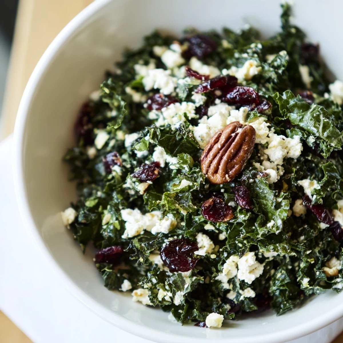 Close-up of a vibrant Winter Kale Salad with Pecans and Cranberries revealing crisp textures, sweet dried fruit, and savory cheese crumbles.