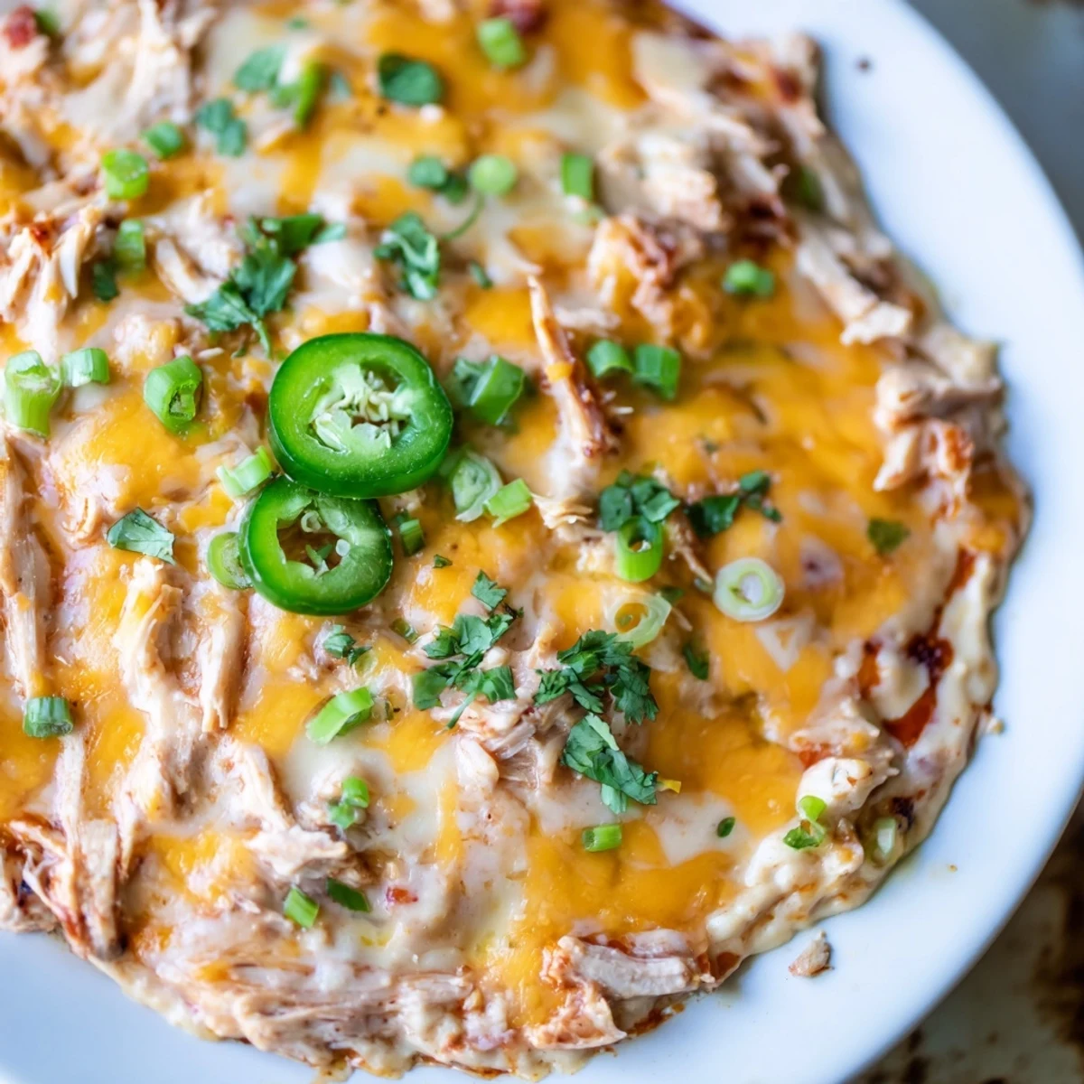 A warm, bubbly skillet of Chicken Enchilada Dip, topped with melted cheddar, Monterey Jack, and fresh cilantro.