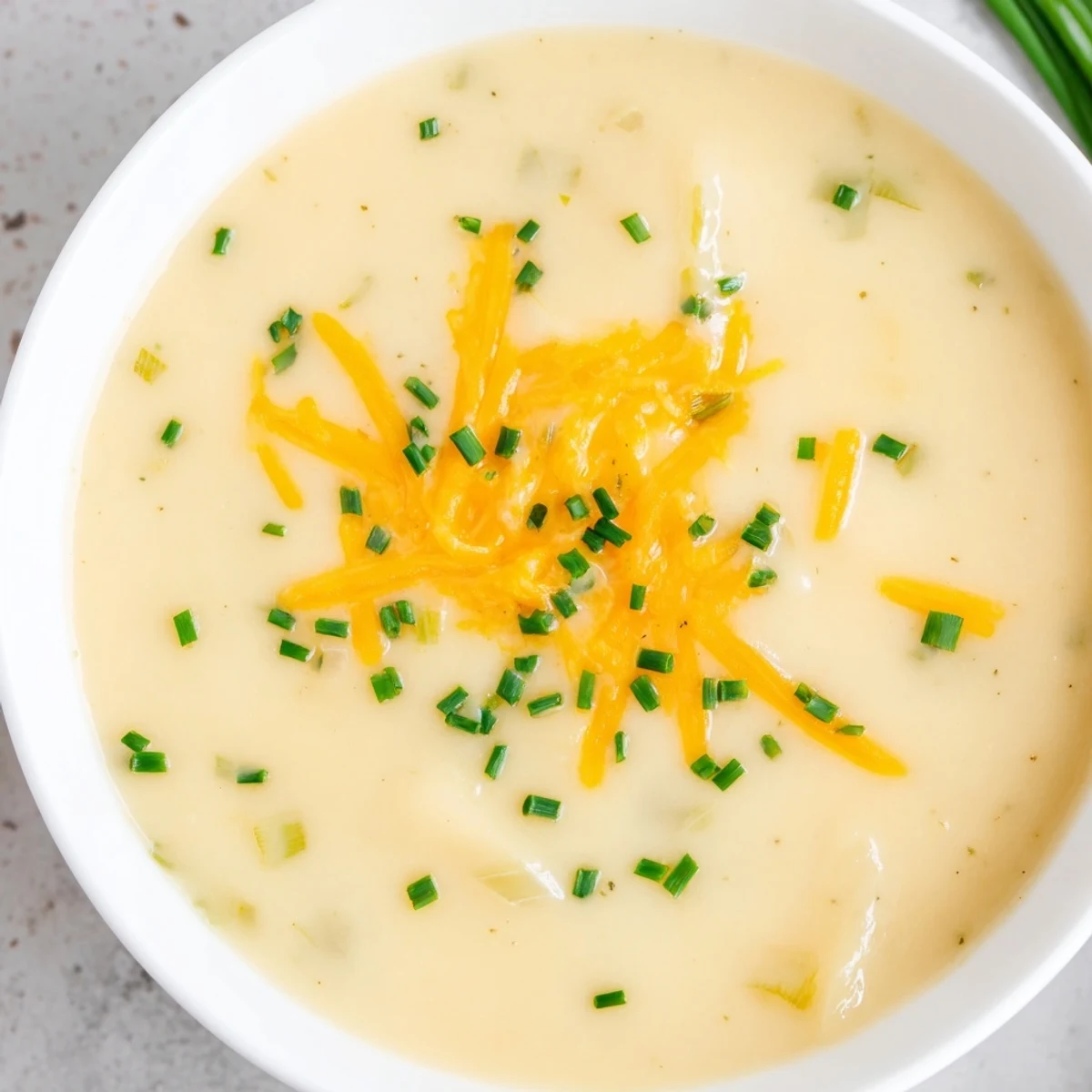 Creamy Irish Potato Leek Soup with Cheddar in a rustic bowl, garnished with fresh chives and extra cheese.