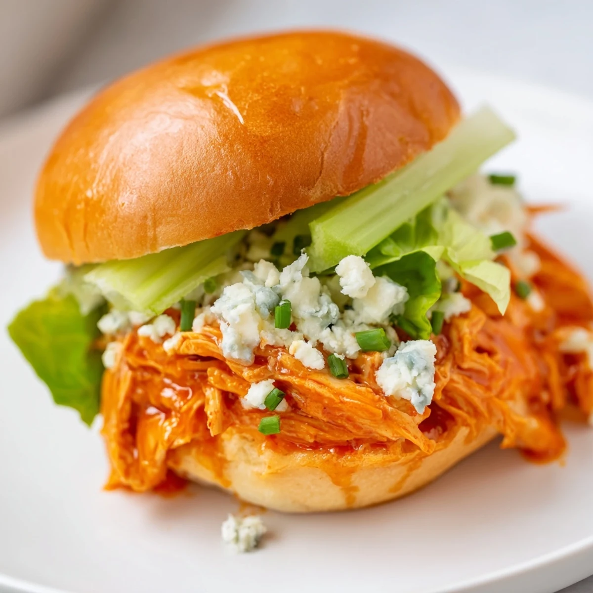Freshly prepared Buffalo Chicken Sliders with Blue Cheese, featuring shredded chicken, celery, and chives on toasted buns.  