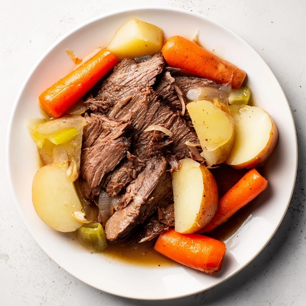A close-up of Slow Cooker Beef Pot Roast with Root Vegetables, featuring tender shredded beef, carrots, parsnips, and potatoes in a rich, savory gravy.