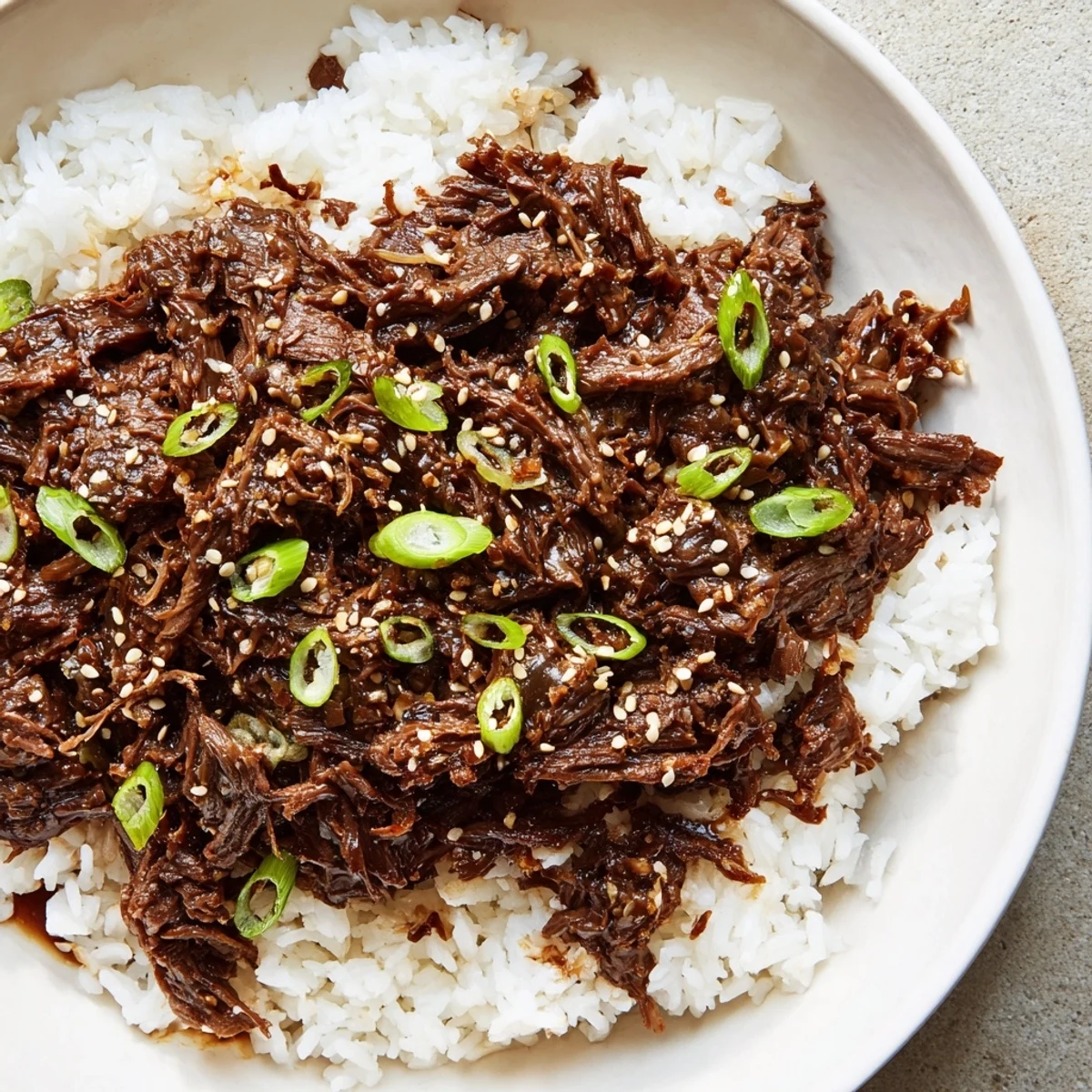 Tender Slow Cooker Korean Beef shreds easily in a savory-sweet sauce, served over fluffy steamed rice for a comforting meal.
