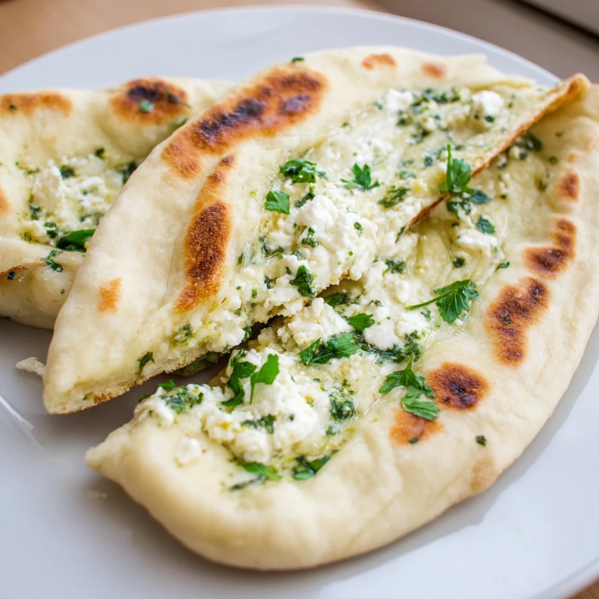 Warm Cottage Cheese Garlic Naan with melted butter and fresh cilantro on a plate.
