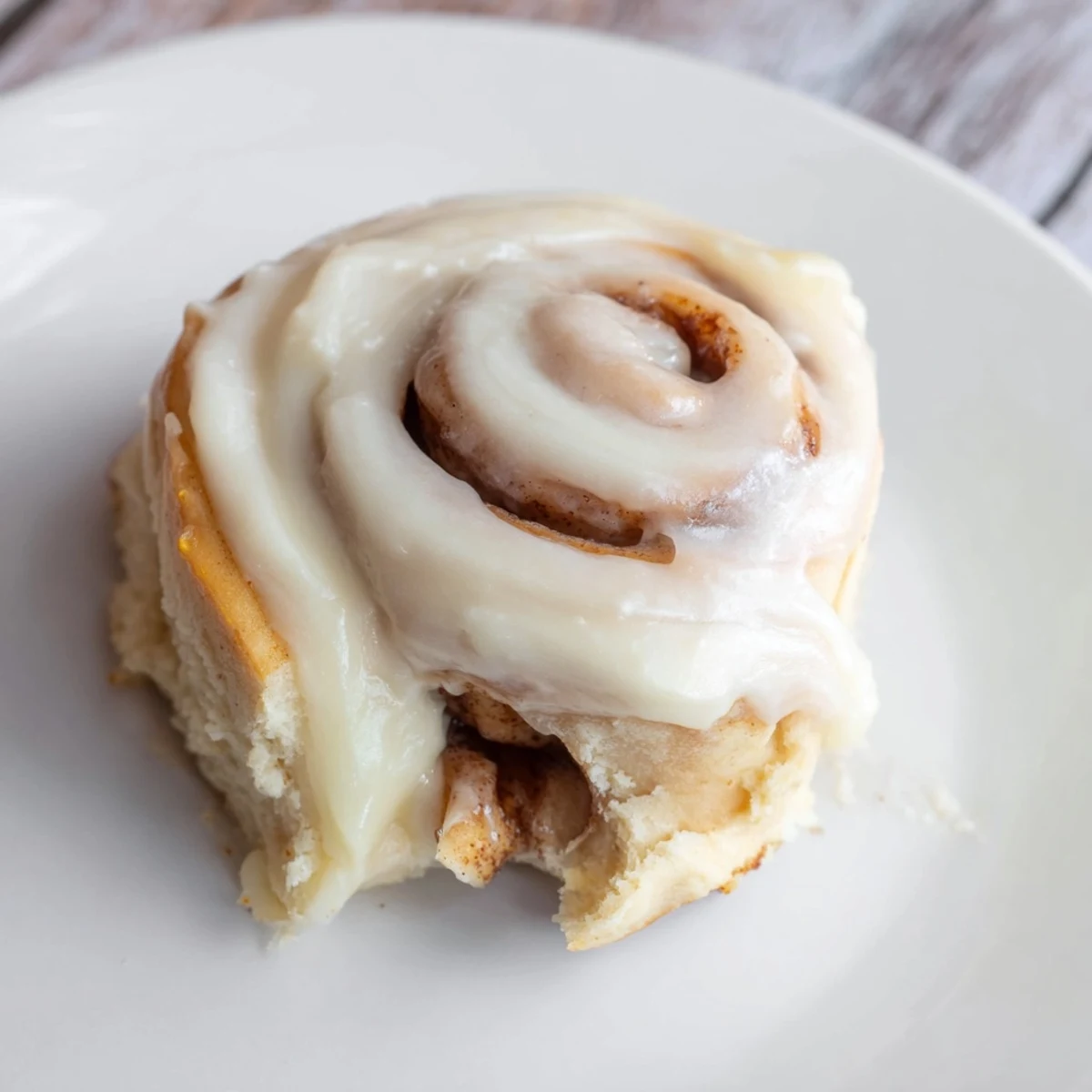 Warm Keto Cinnamon Buns topped with creamy icing are served on a rustic wooden board for breakfast.