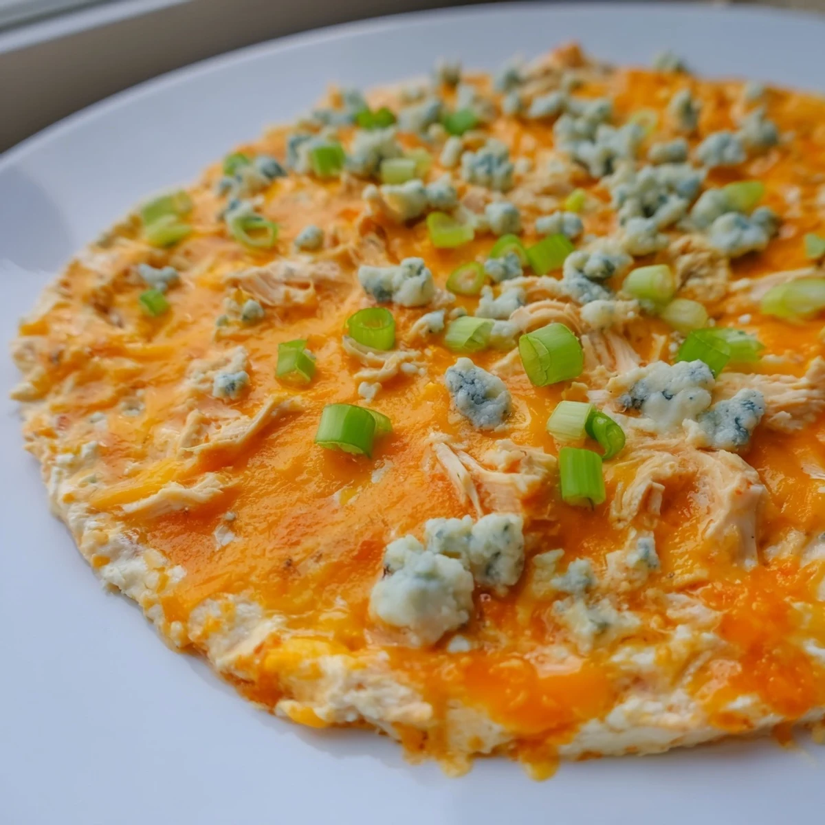 Golden, cheesy Keto Buffalo Chicken Dip straight from the oven on a rustic wooden table.