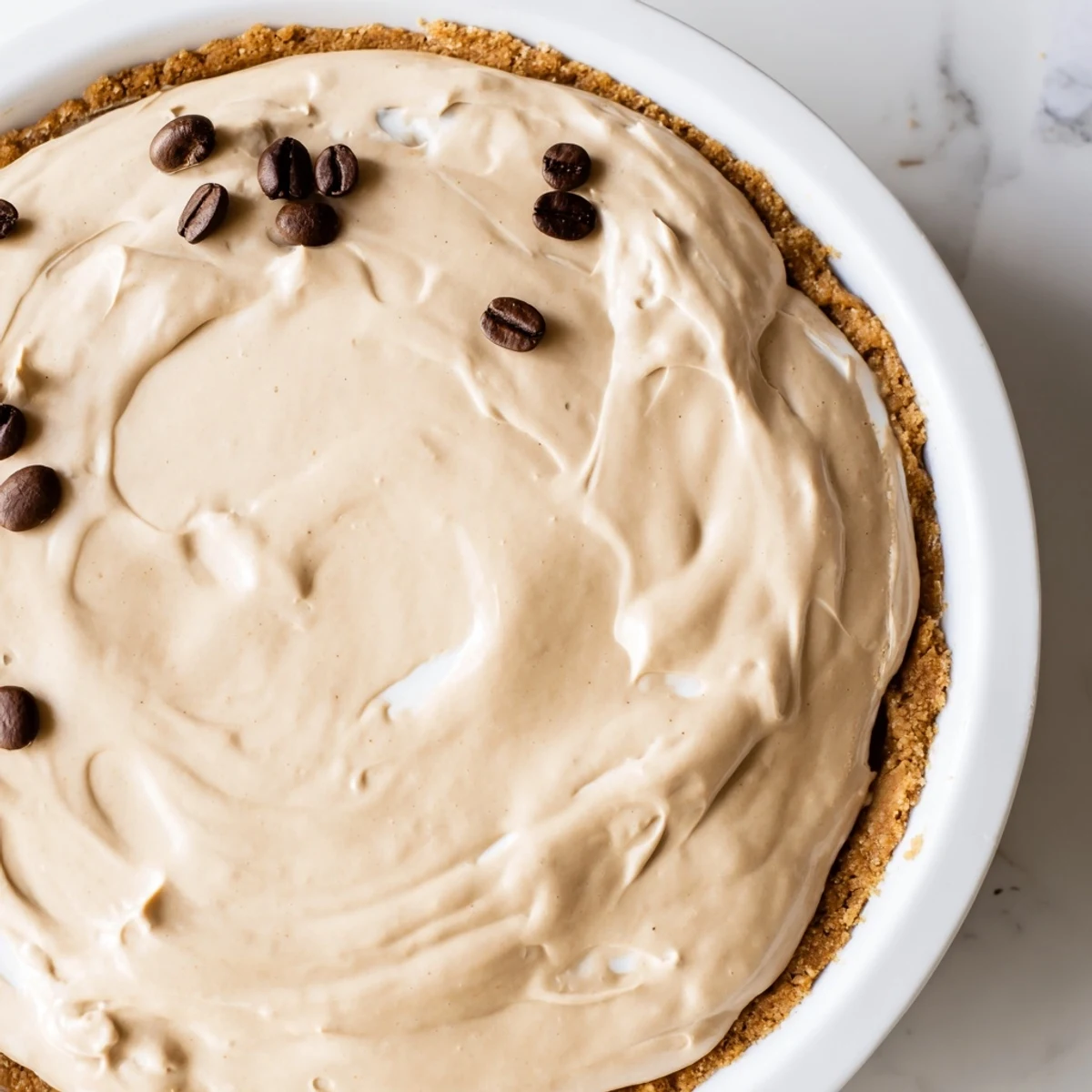 Creamy Keto Cold Brew Coffee Pie with almond flour crust, topped with luscious whipped cream and coffee bean garnish.
