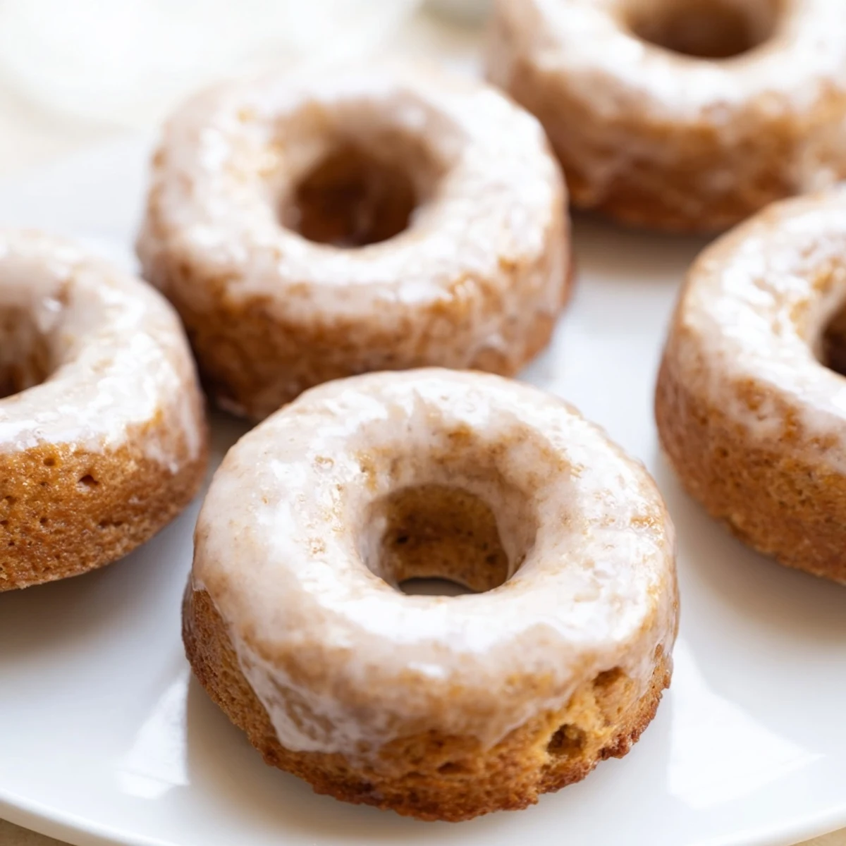Warm Baked Banana Bread Donuts on a wire rack, showing their moist crumb and speckles of cinnamon and nutmeg.