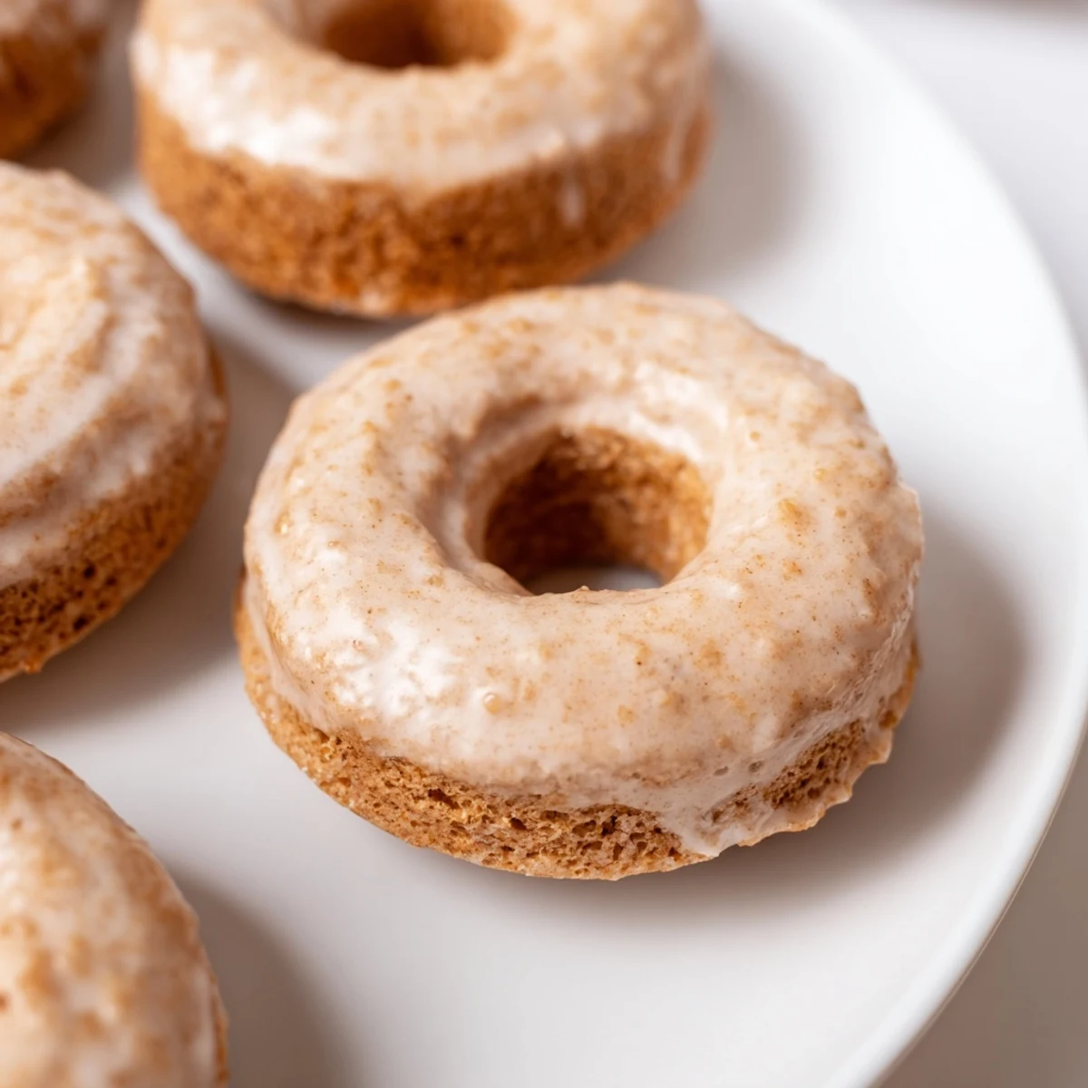 Stack of glazed Baked Banana Bread Donuts with ripe bananas nearby, highlighting their soft texture and comforting aroma.