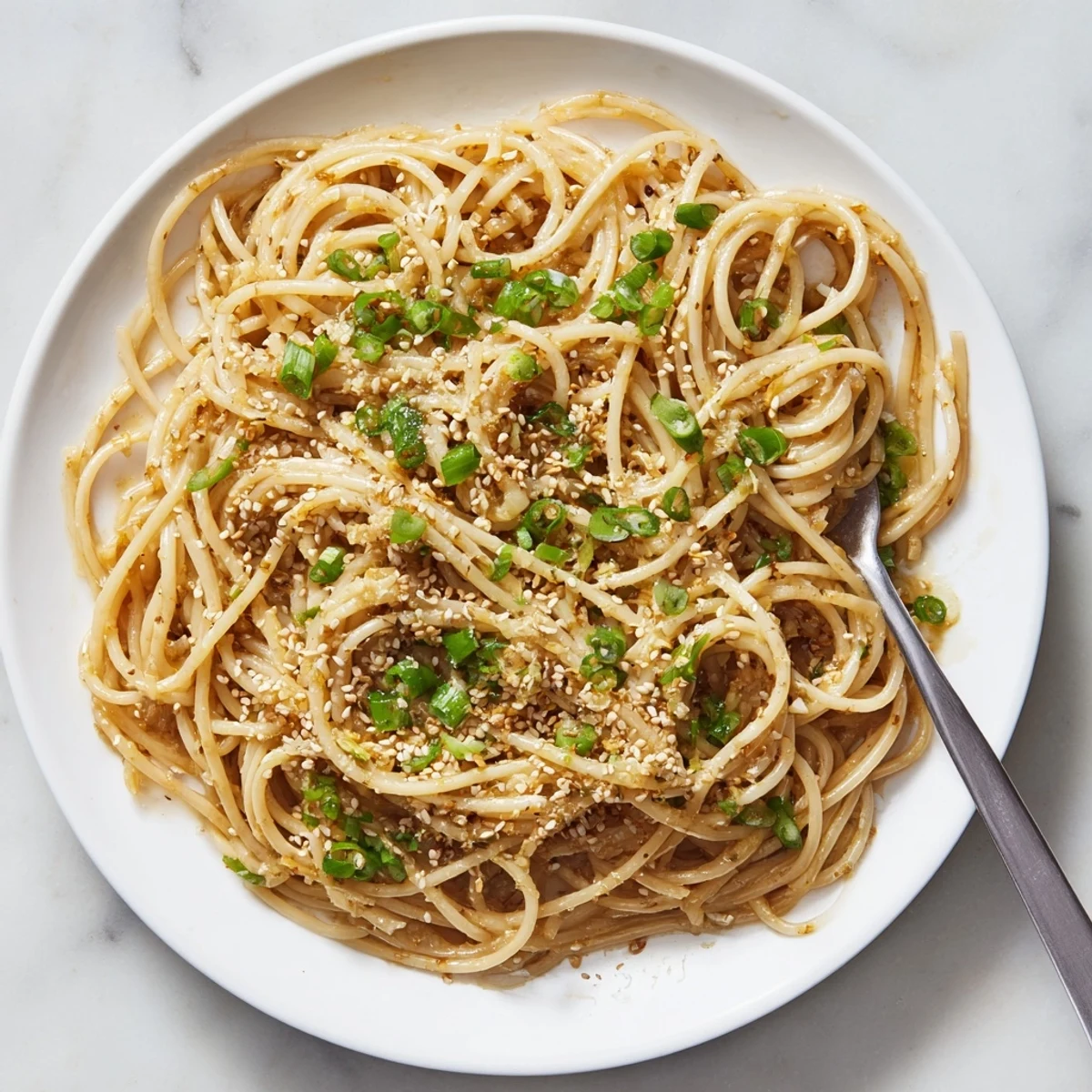 Steaming garlic noodles tossed in a buttery soy sauce with fresh scallions garnish.