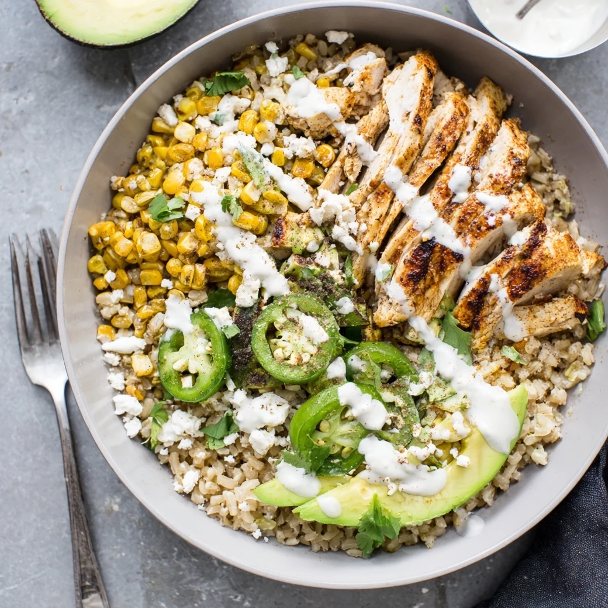 Vibrant Mexican-inspired Street Corn Chicken Bowl topped with tangy crema, jalapeños, and green onions served warm for dinner.