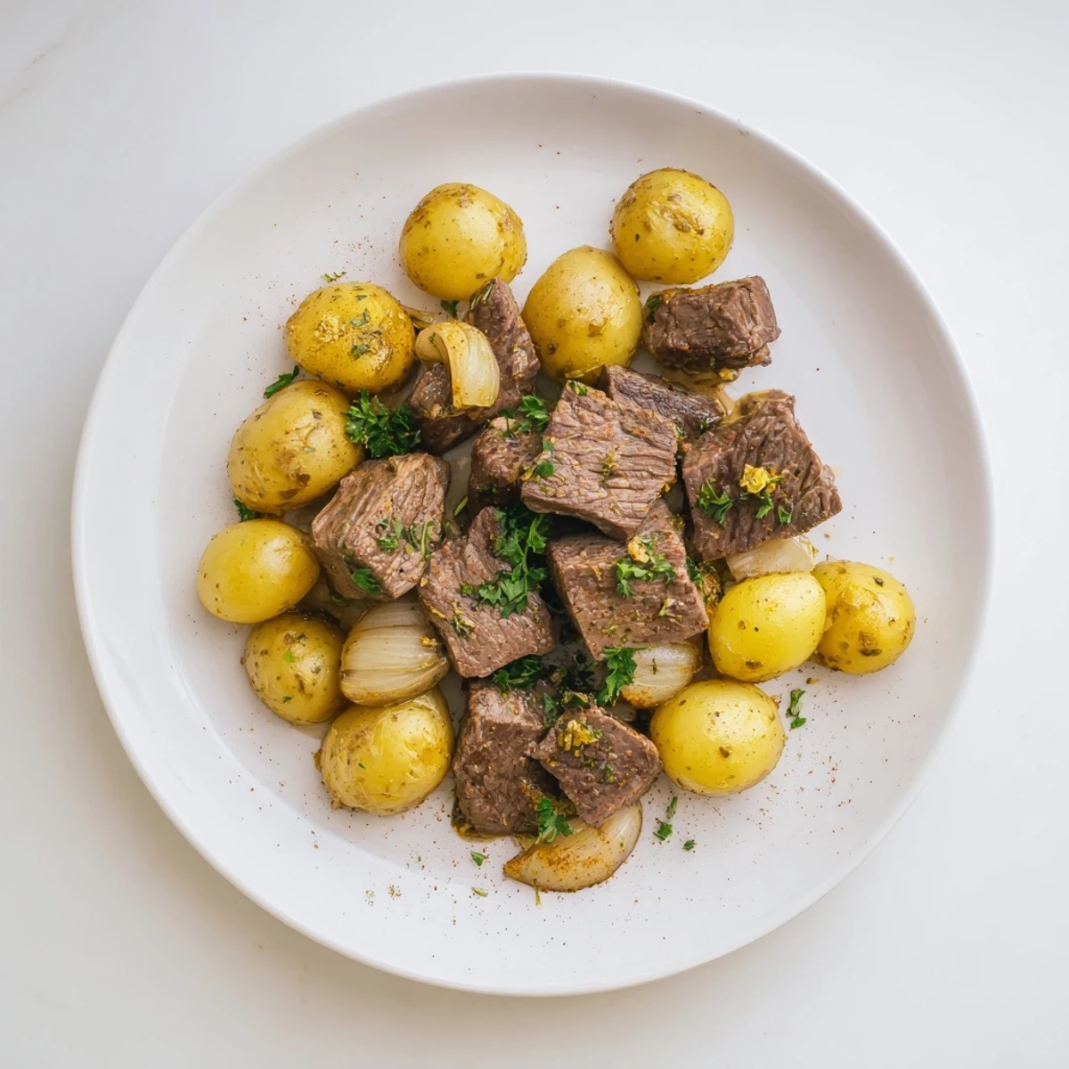 A close-up shows the slow cooker garlic butter beef with potatoes beside fresh parsley garnish and a wooden serving spoon.