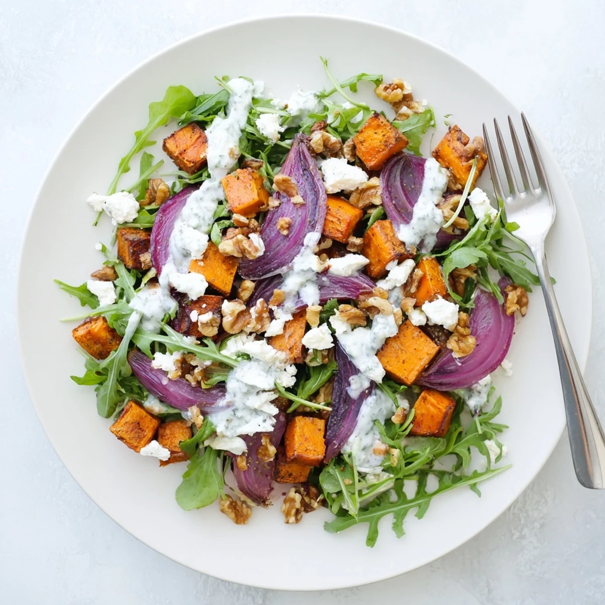 Vibrant creamy roasted beet salad featuring sweet potato cubes, tangy feta cheese, and walnuts drizzled with luscious yogurt dressing