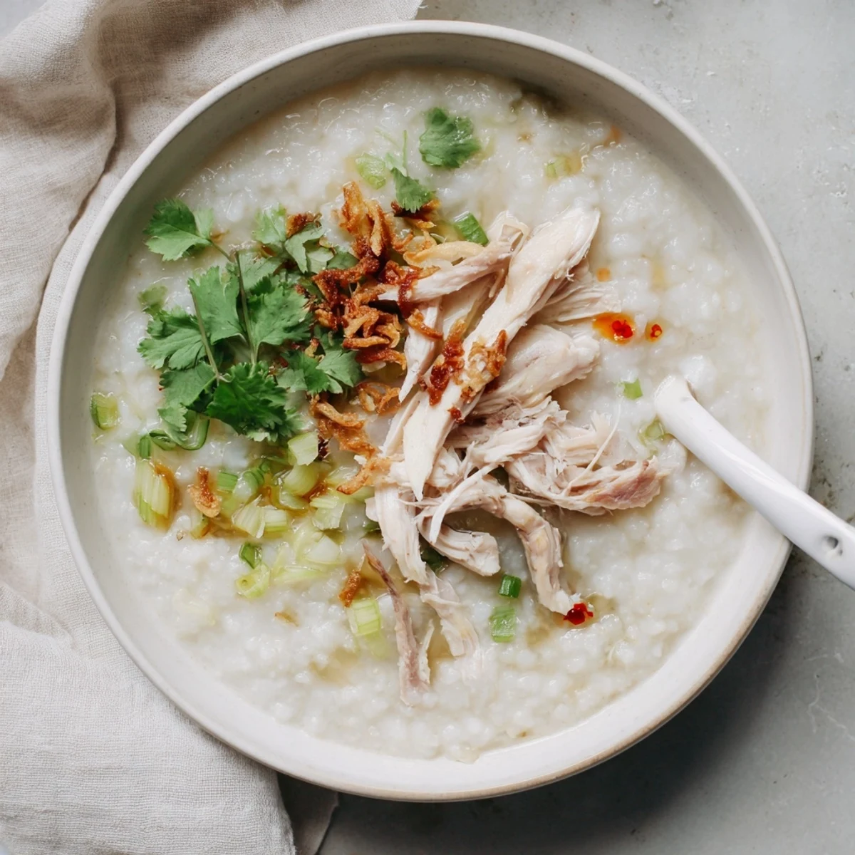 Creamy leftover Thanksgiving turkey congee topped with scallions, cilantro, and crispy shallots in a bowl.