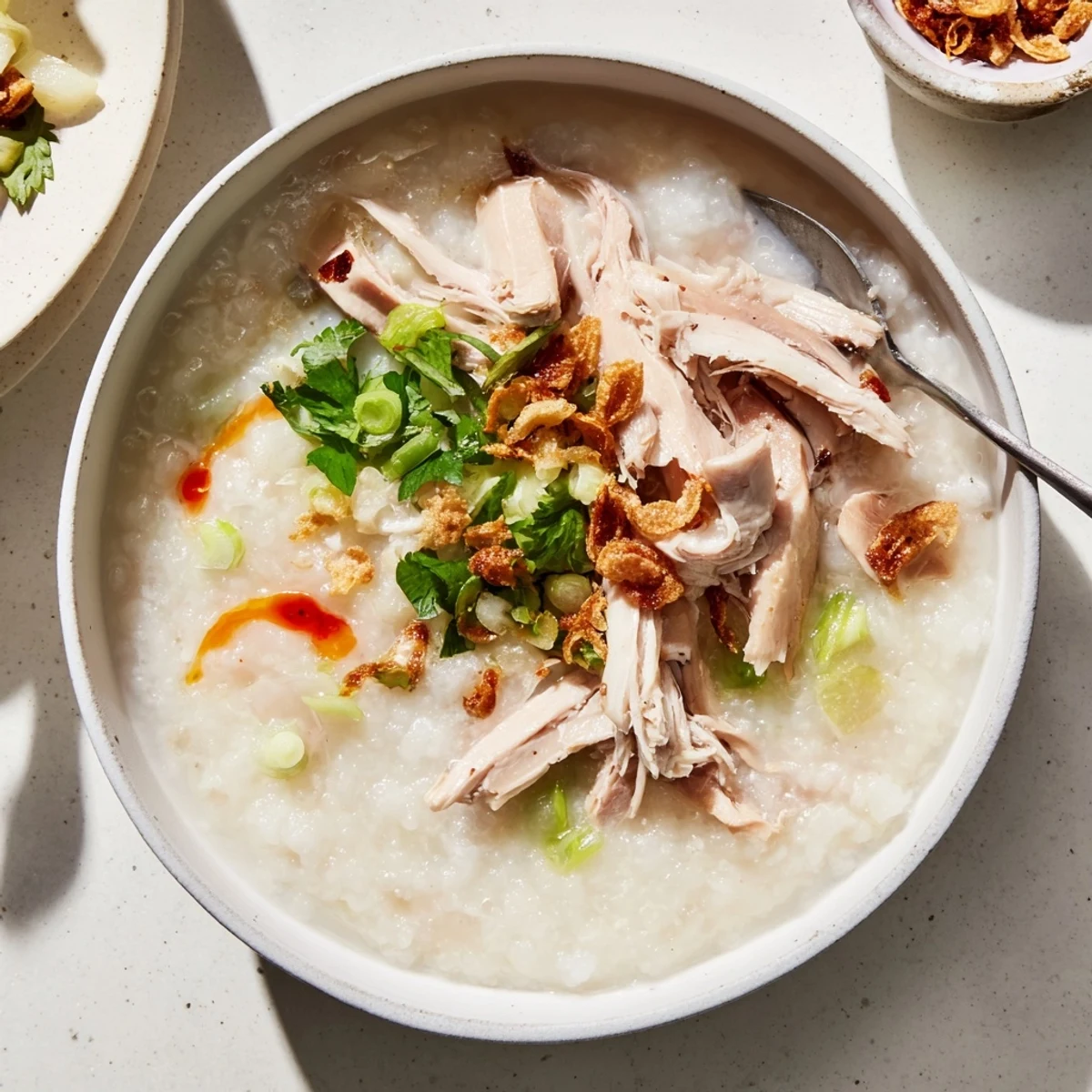 Steaming bowl of Asian-inspired leftover Thanksgiving turkey congee garnished with fresh herbs and boiled egg.