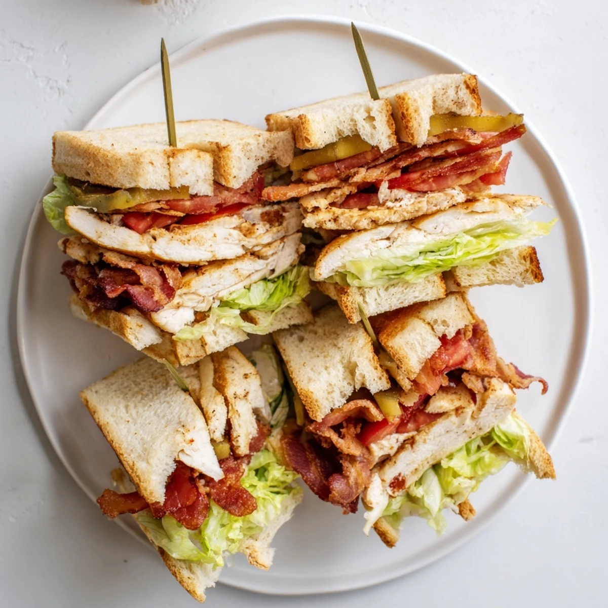 Triple-decker chicken club sandwich stacked with crispy bacon, fresh lettuce, and juicy tomato slices on golden toasted bread