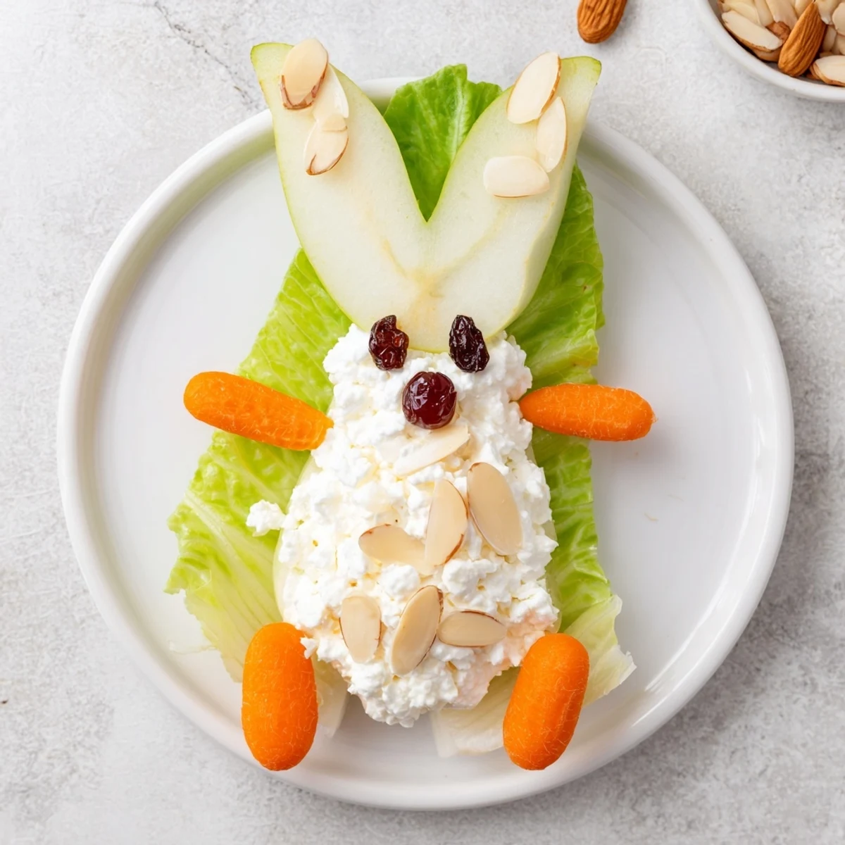 Adorable pear bunny salad featuring cottage cheese tails, carrot whiskers, and cherry noses on fresh lettuce leaves