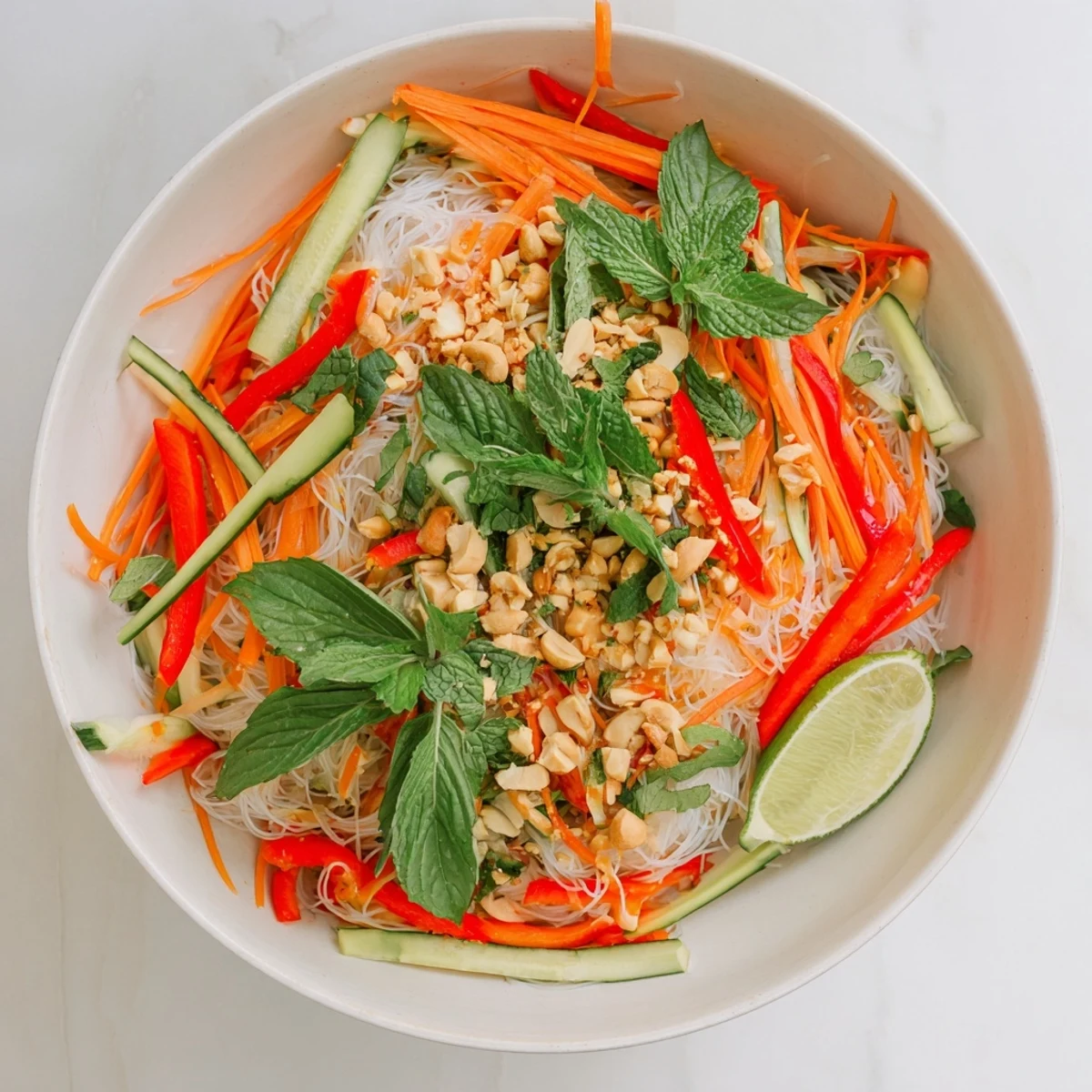 Light Vietnamese noodle salad arranged with vibrant sliced peppers, bean sprouts, and fragrant mint drizzled with tangy sauce.