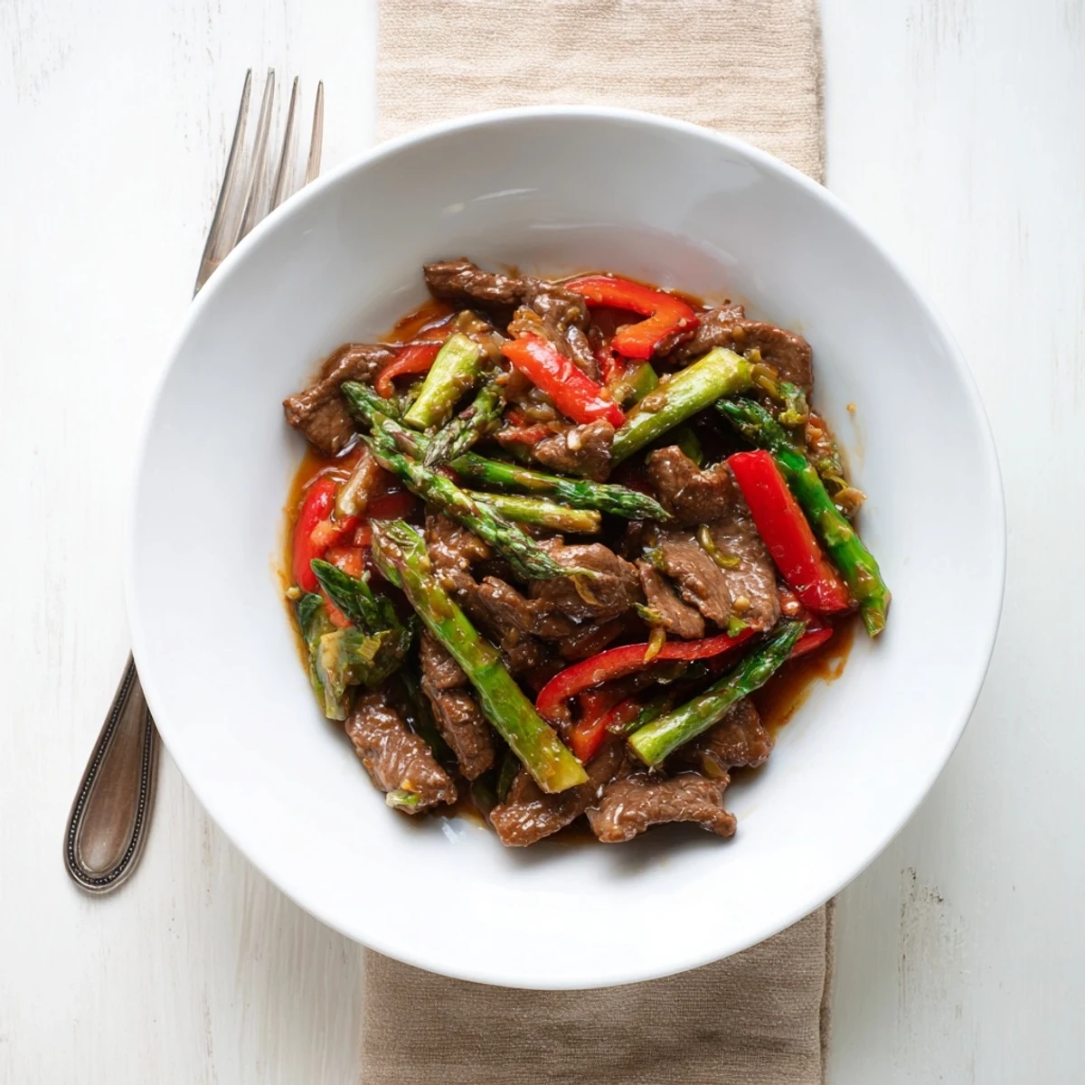 Close-up of soy beef bok choy and asparagus stir fry coated in rich glossy sauce