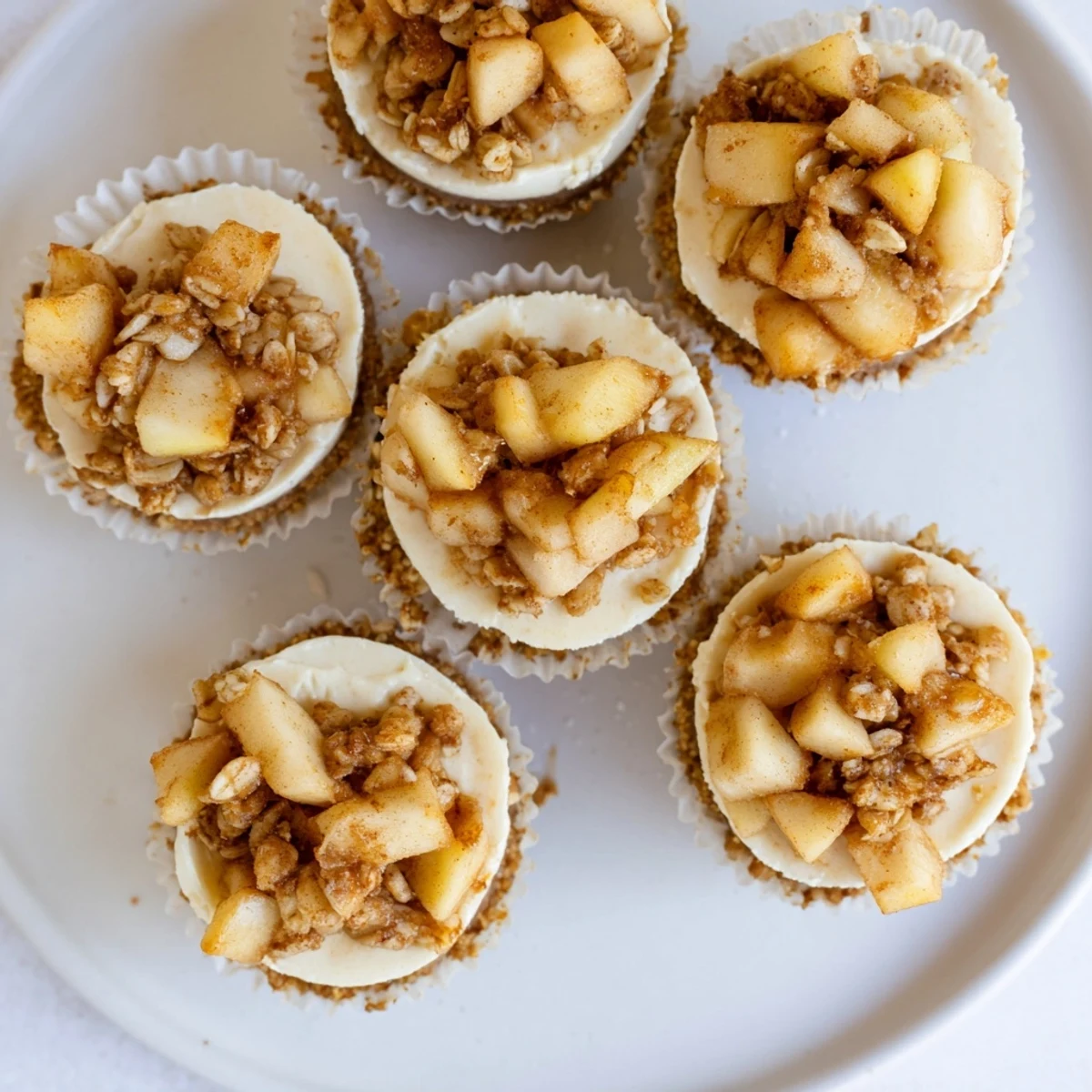 Golden apple crisp topping crowns creamy mini cheesecakes in individual portions for dessert