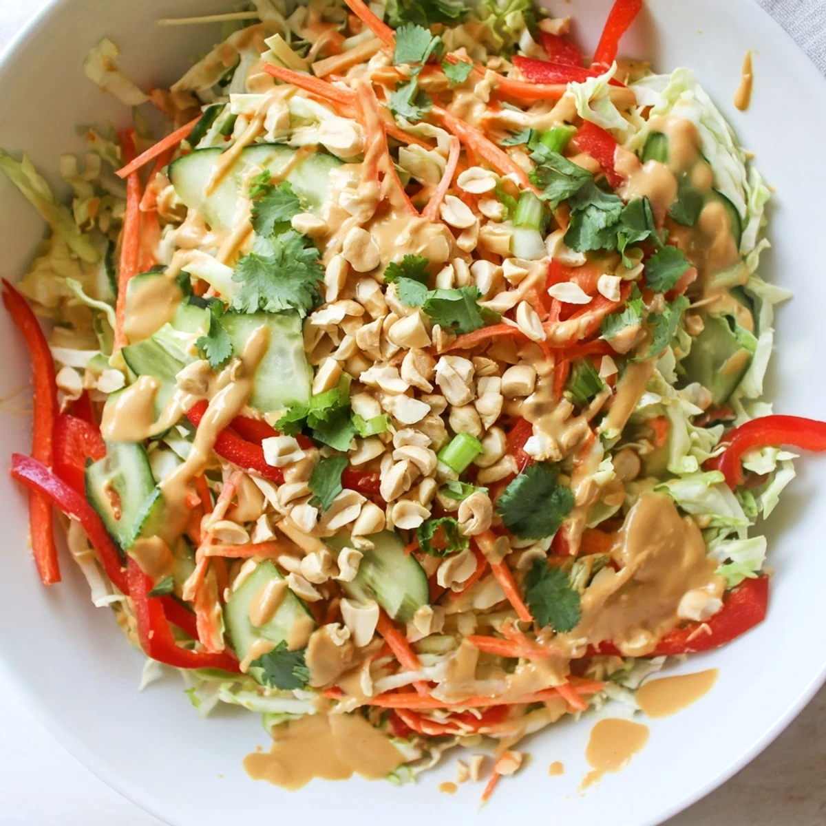 Vibrant crunchy cabbage salad topped with creamy Thai peanut dressing and crushed roasted peanuts.