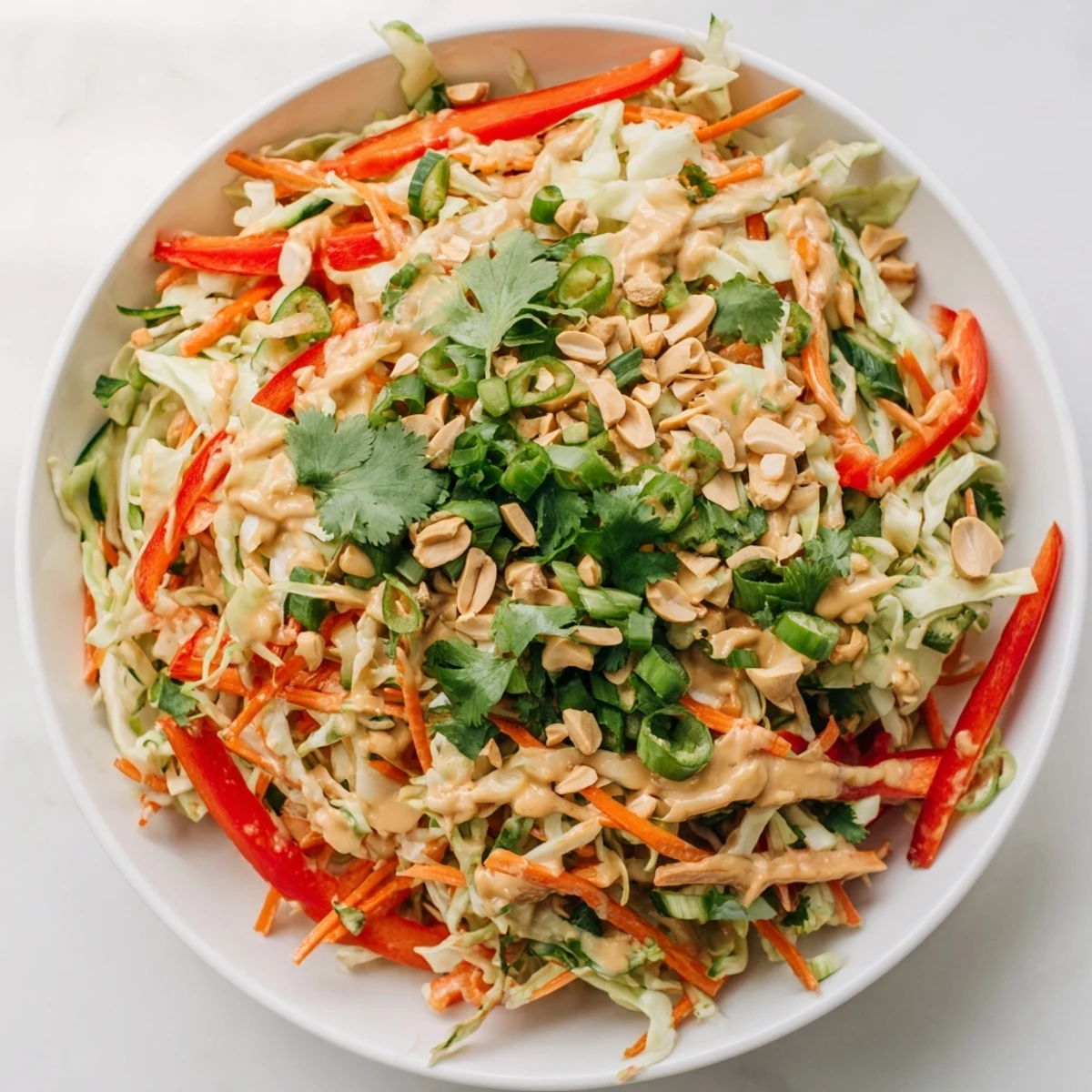 Simple Thai salad peanut sauce coating crisp julienned vegetables topped with fresh cilantro leaves.