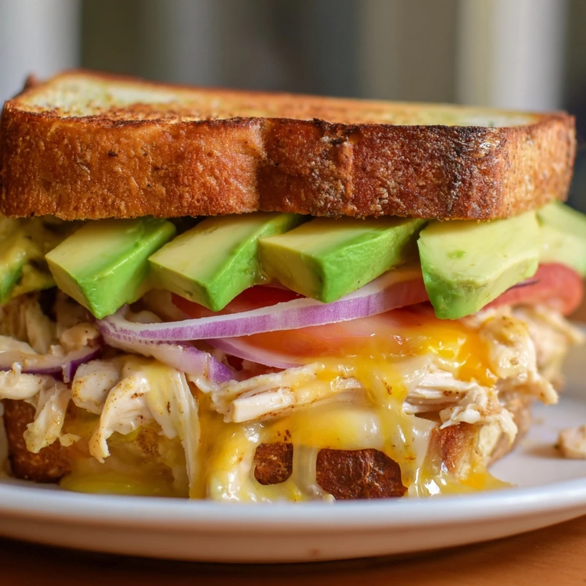 Sliced chicken avocado melt sandwich showing tender chicken ripe avocado and melted cheese between bread