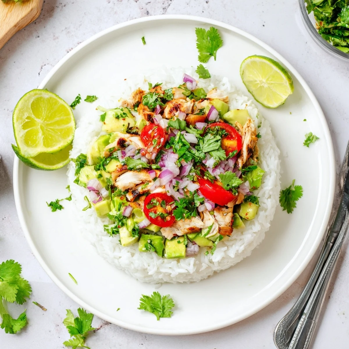 Stacked honey lime chicken avocado rice bowl with fresh cilantro garnish and lime wedges