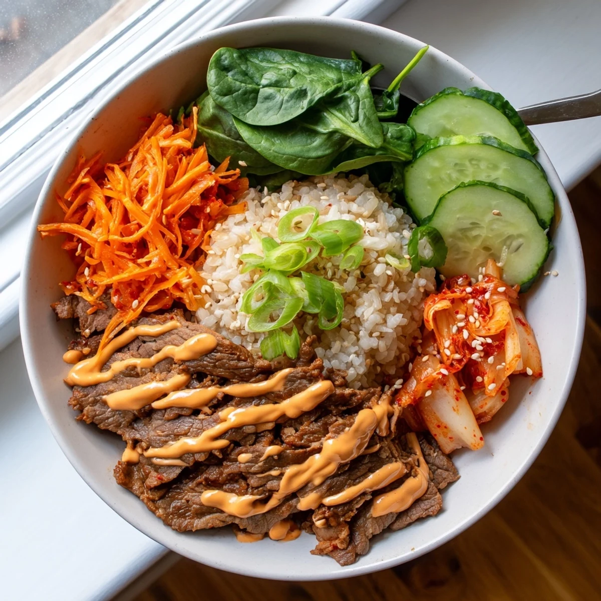 Caramelized sliced steak over fluffy jasmine rice in Korean BBQ steak rice bowls with spicy cream sauce
