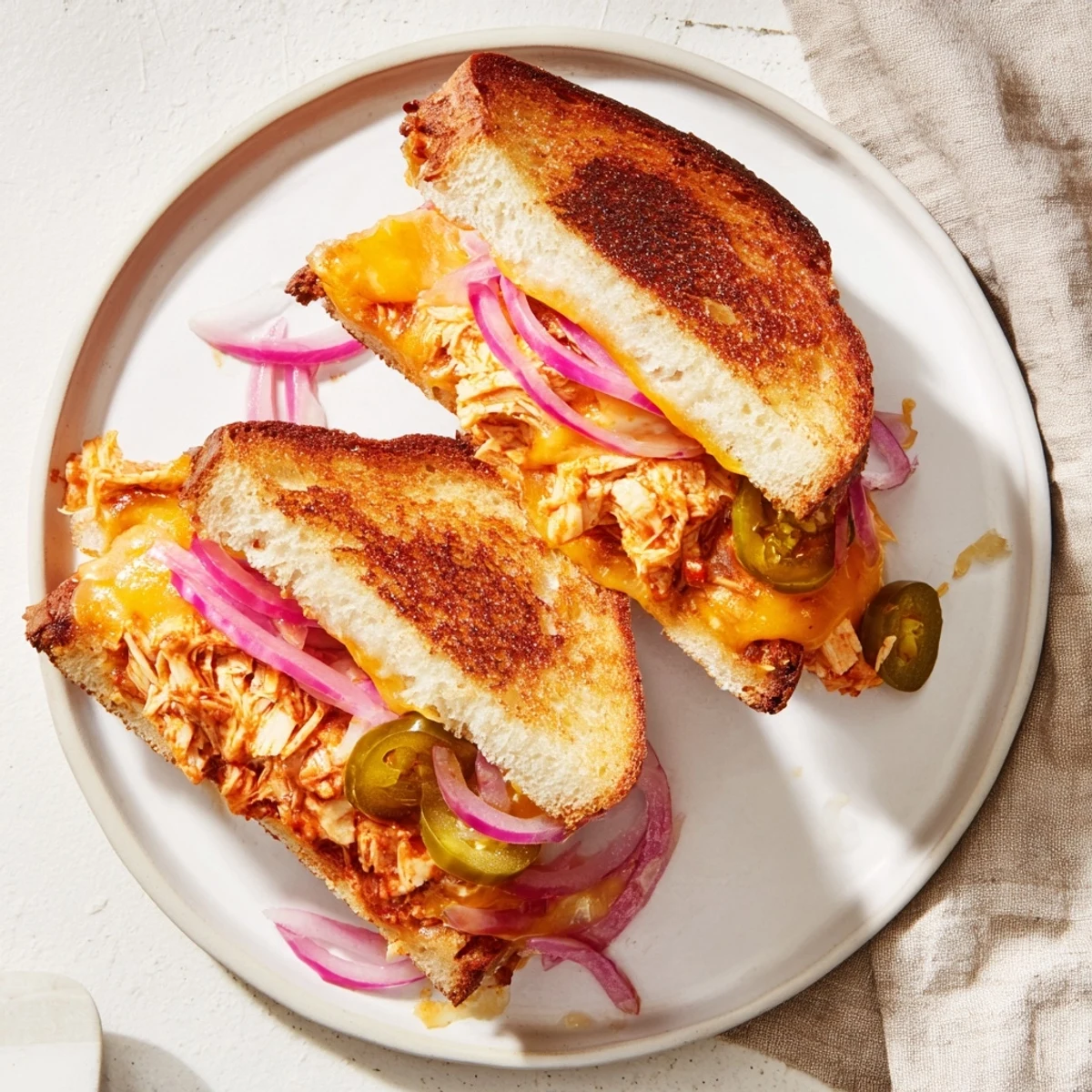 Sliced BBQ chicken grilled cheese sandwich oozing melted cheese on sourdough bread