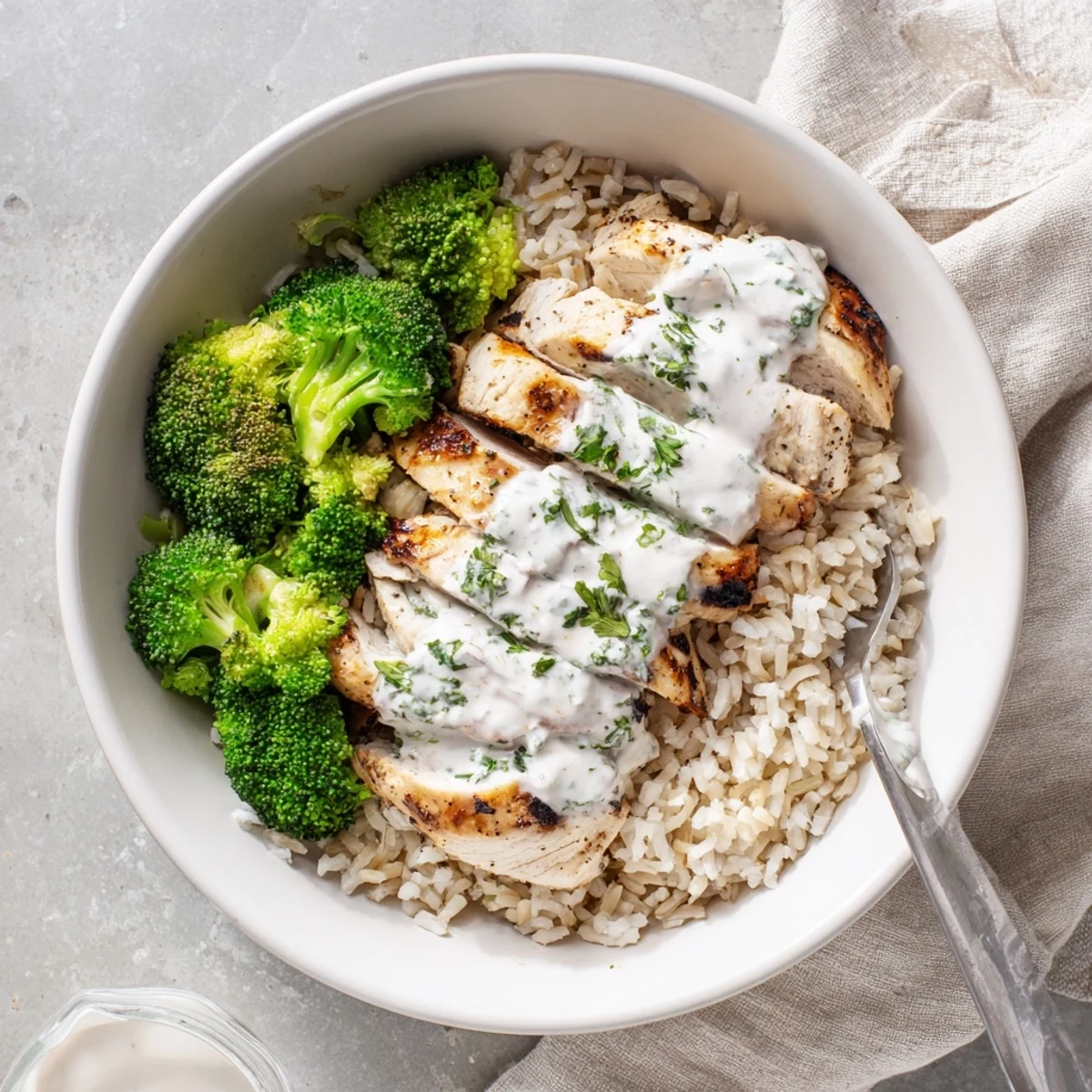 Healthy grilled chicken broccoli bowl with protein-rich Greek yogurt garlic sauce served for a nutritious dinner