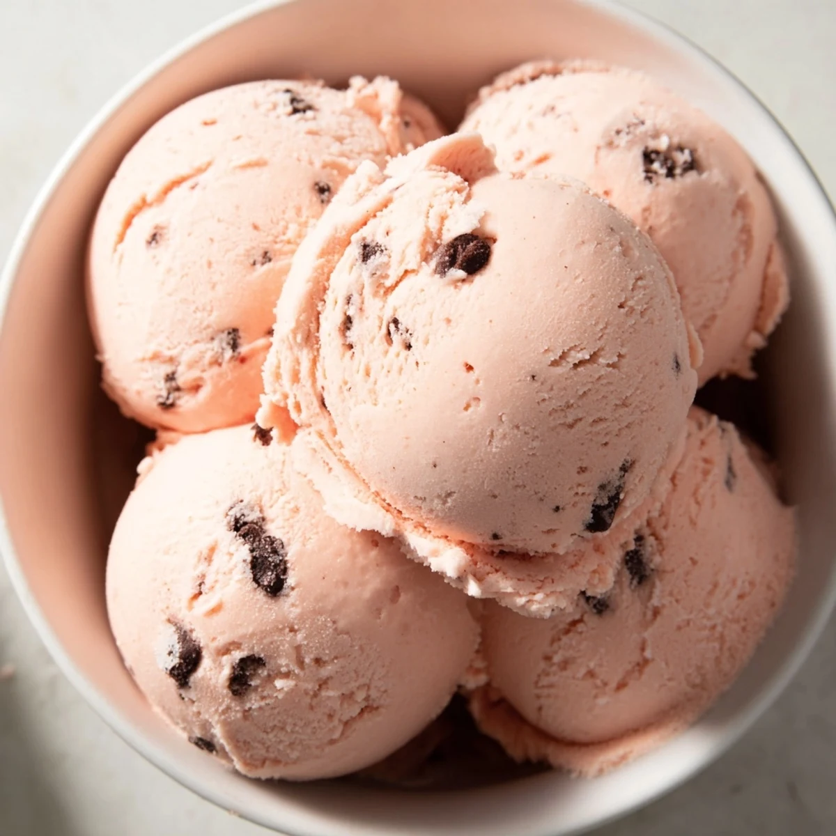 Smooth frozen watermelon ice cream swirl topped with lime zest on a wooden serving board