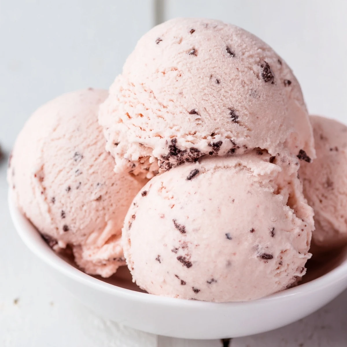 Pink scoops of refreshing watermelon ice cream stacked in a vintage glass dessert dish
