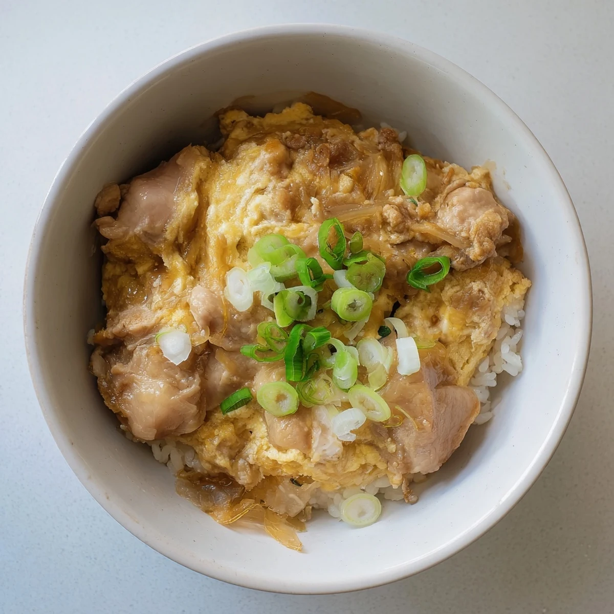 Golden Oyakodon bowl featuring fluffy rice topped with tender chicken and soft-set eggs in savory sauce