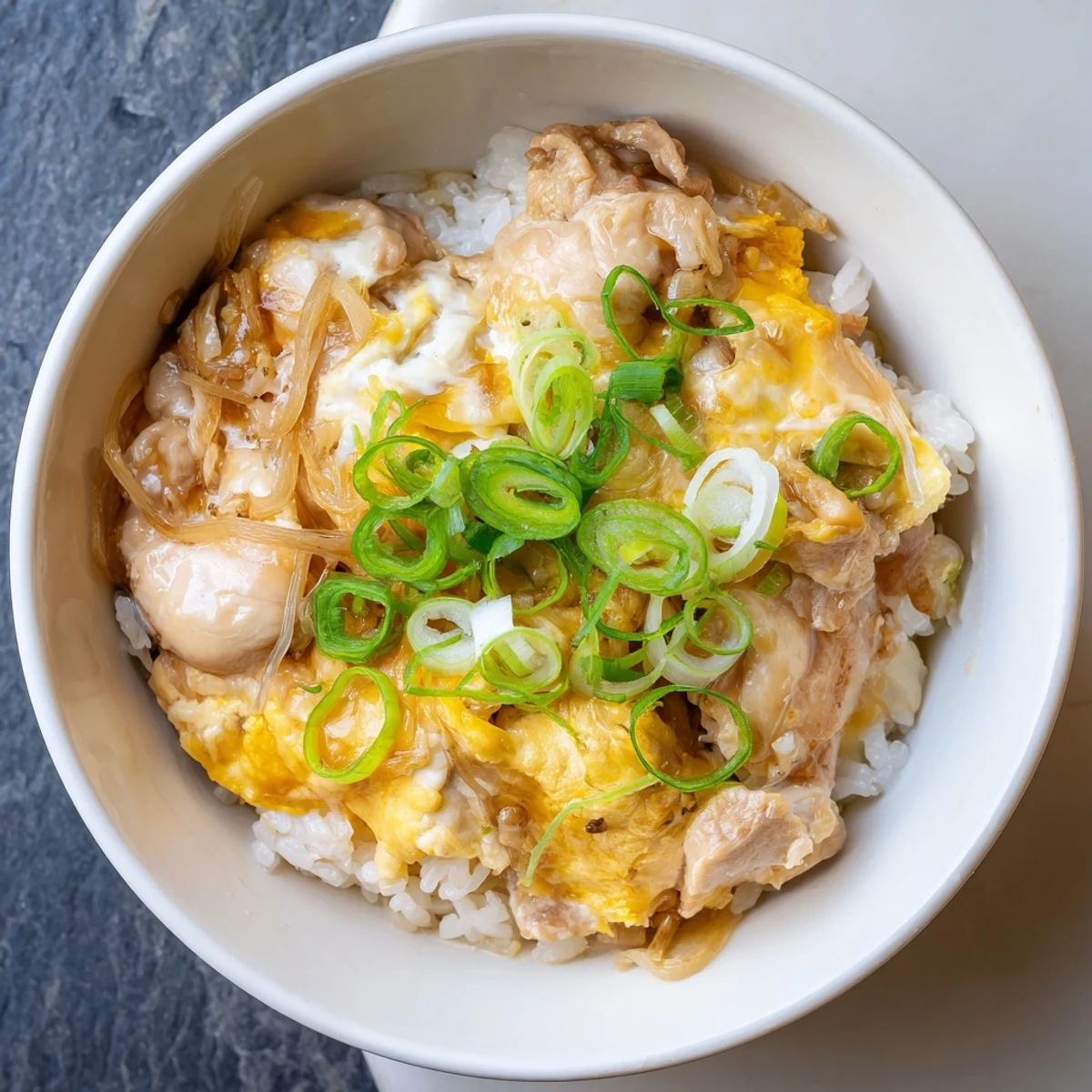 Japanese Oyakodon recipe showcasing succulent chicken pieces and silky eggs simmered in sweet-savory dashi broth over rice