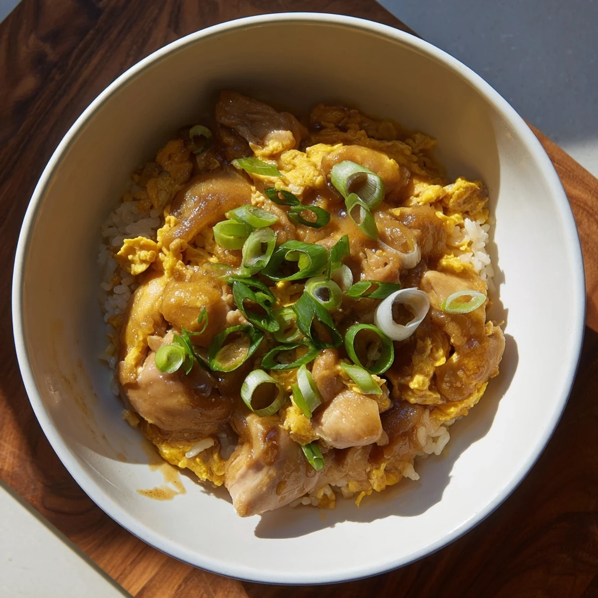 Comforting One Pot Oyakodon served in a deep bowl with steaming rice and garnish of fresh green onions