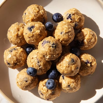 A platter of chilled Blueberry Cheesecake Protein Bites dusted with oats, perfect for a healthy post-workout snack.