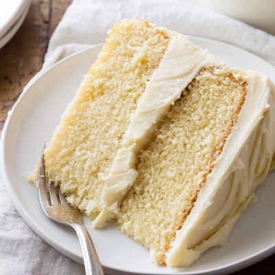 Sliced wedge of Perfect Vanilla Cake revealing moist crumb and creamy vanilla buttercream layers.