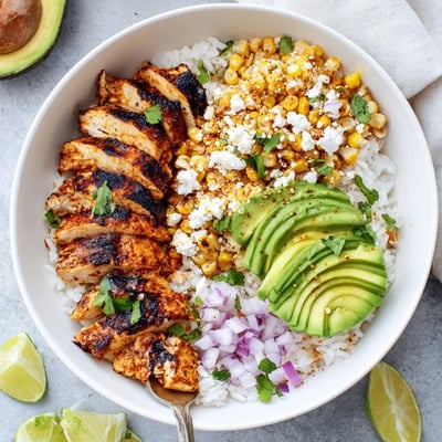 Street Corn Chicken Rice Bowl features fluffy rice, zesty toppings, and lime wedges for serving.